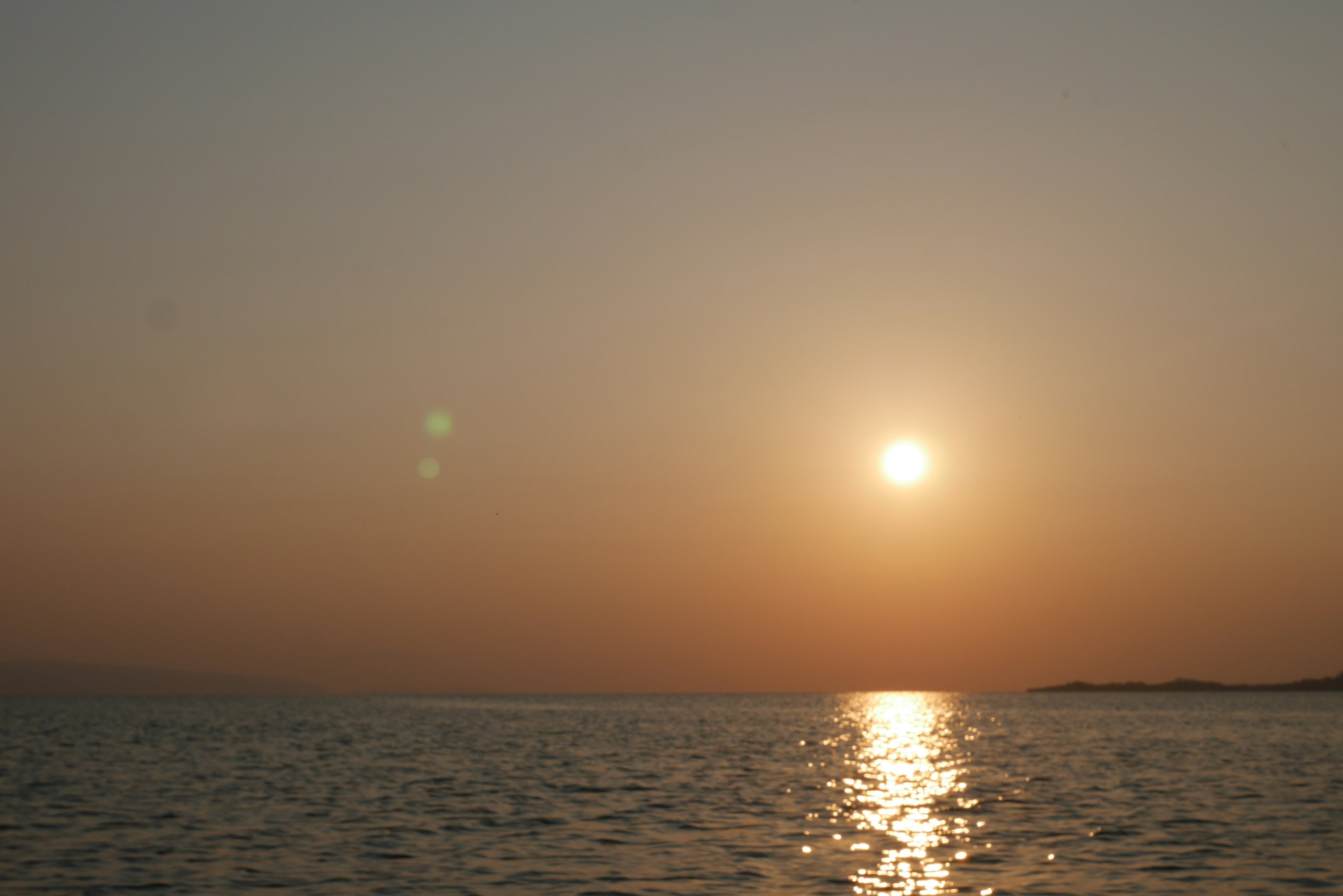 Atardecer naranja sobre el mar con reflejos tranquilos en el agua