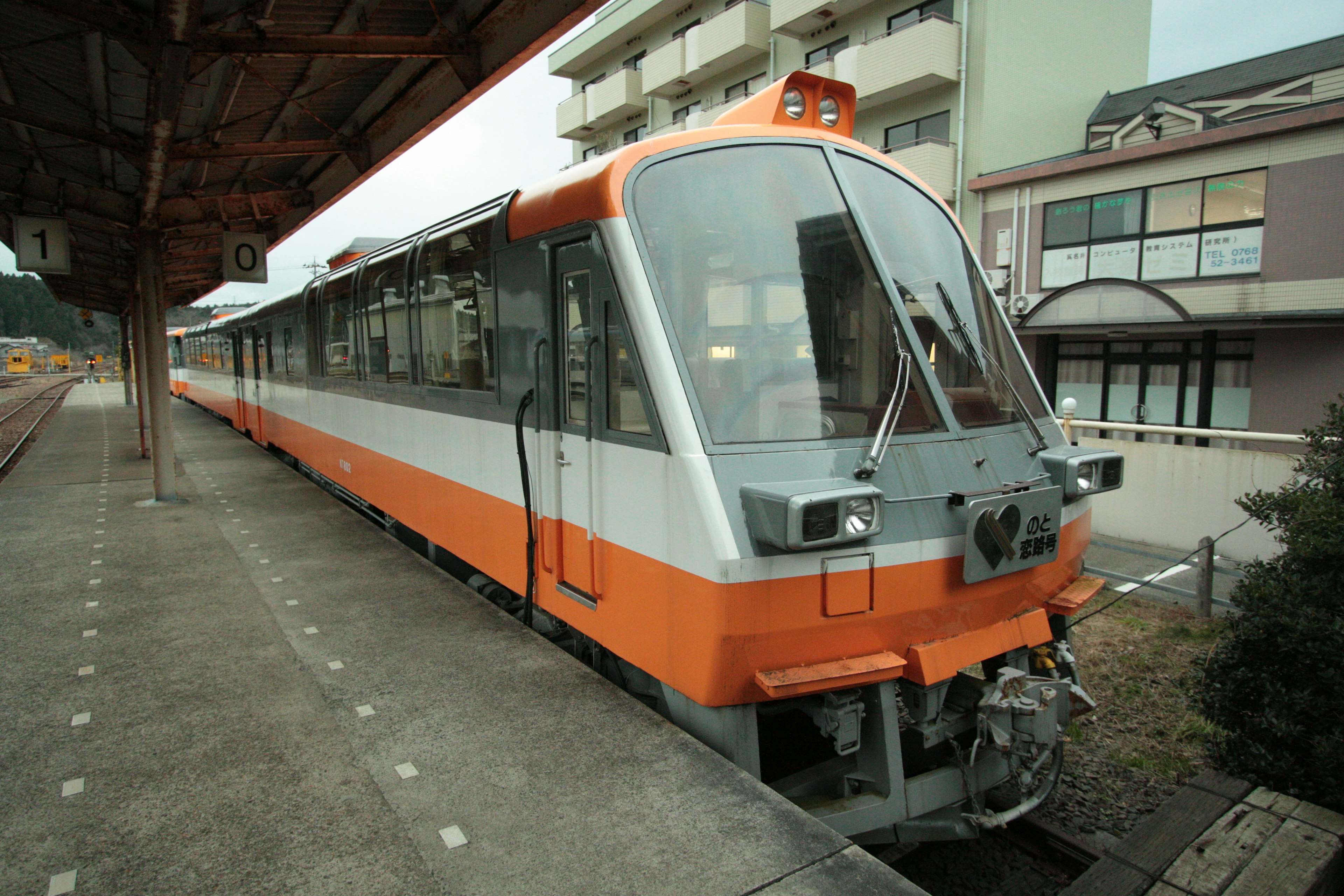 Un treno con esterno arancione in una stazione