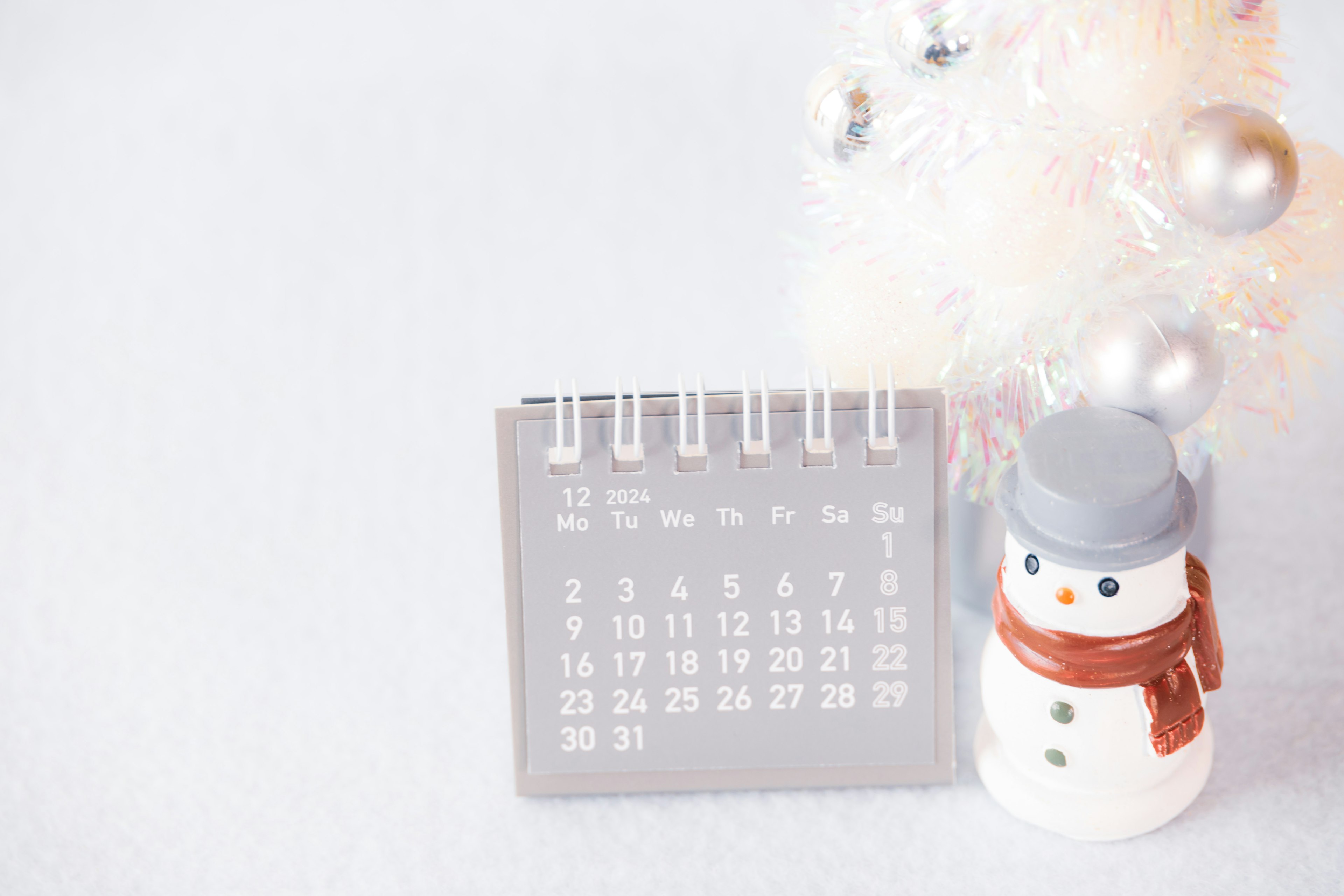 Calendario gris y decoración de muñeco de nieve sobre un fondo invernal