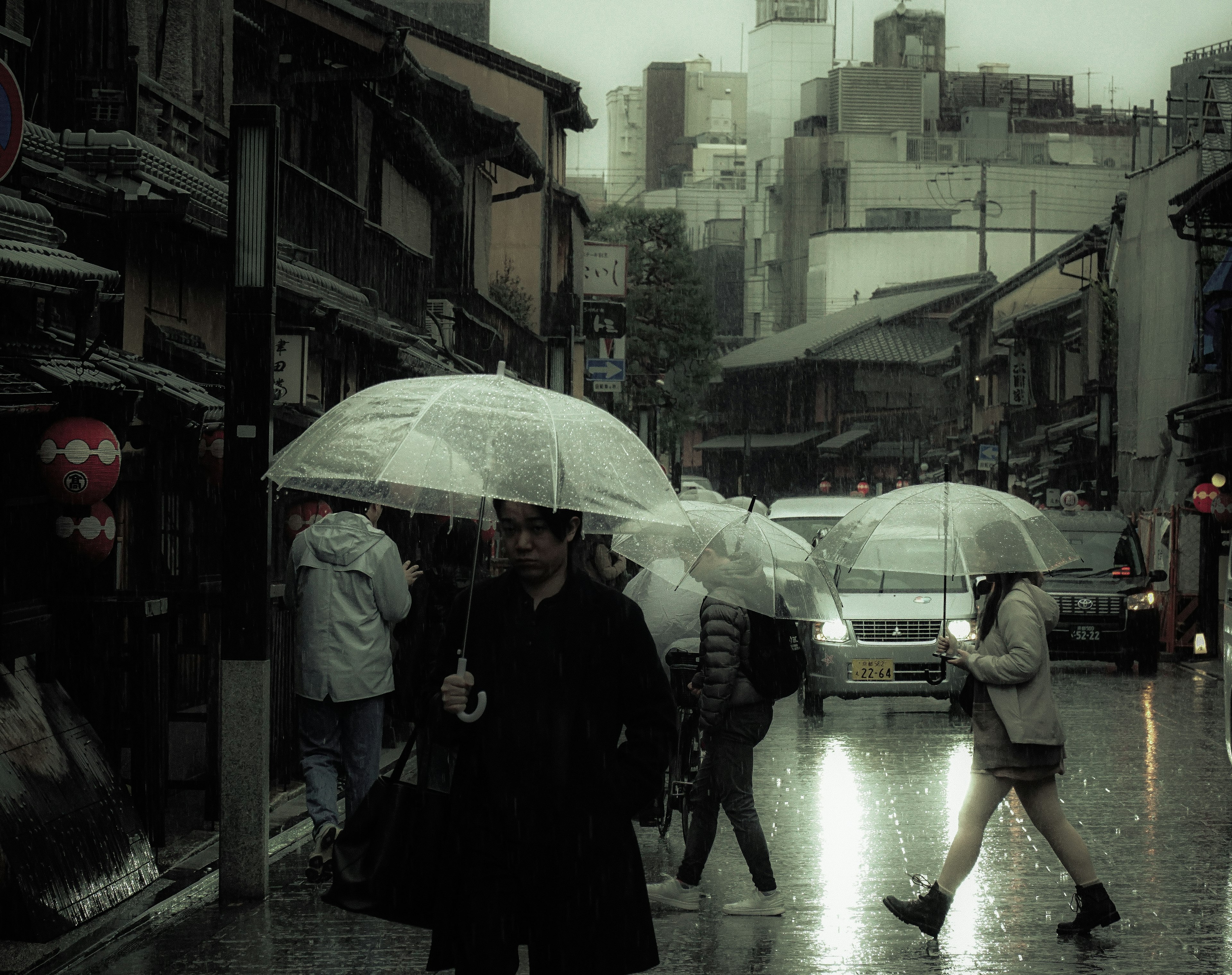 City scene with people walking under umbrellas in the rain