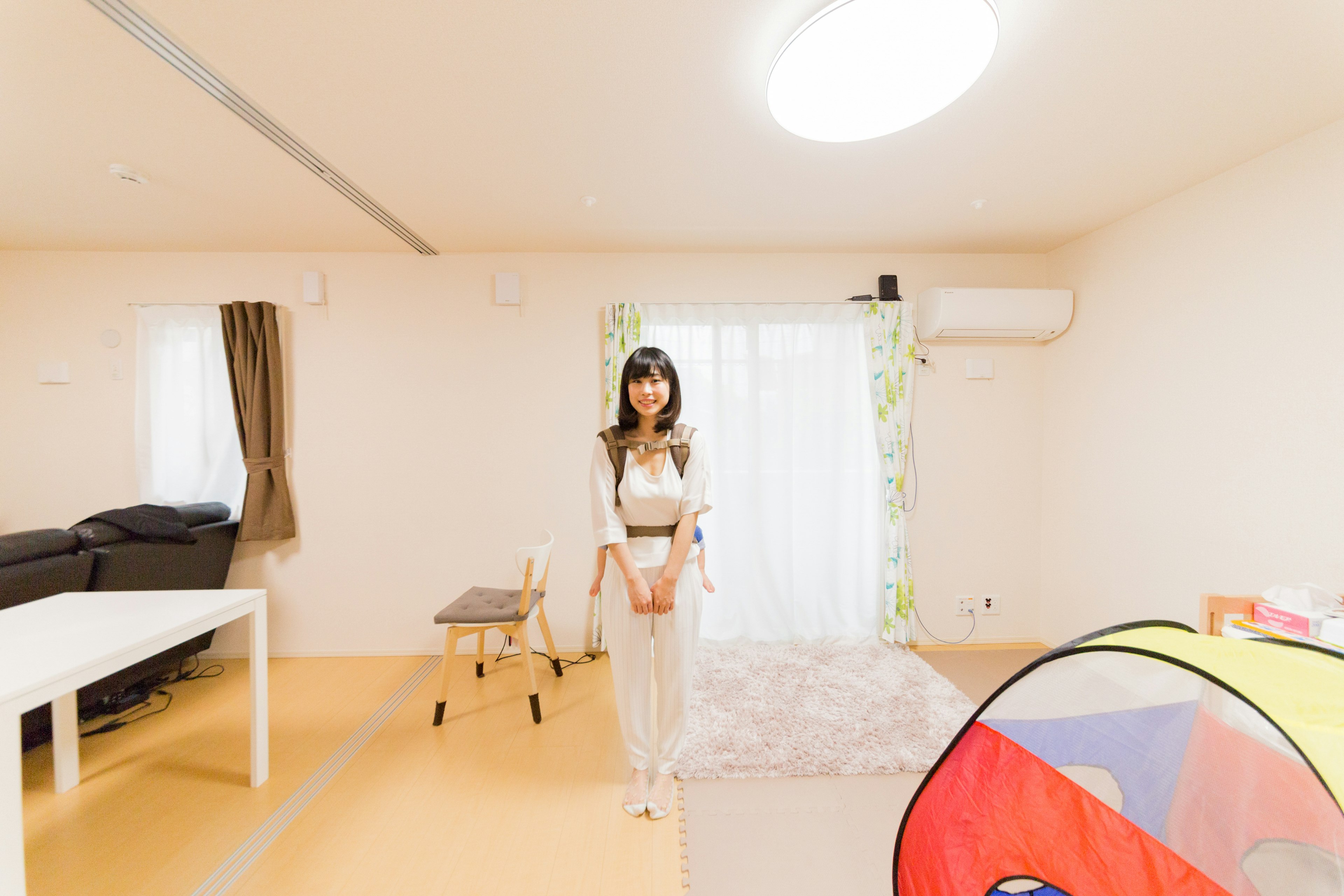 A woman standing in a bright room with a colorful tent