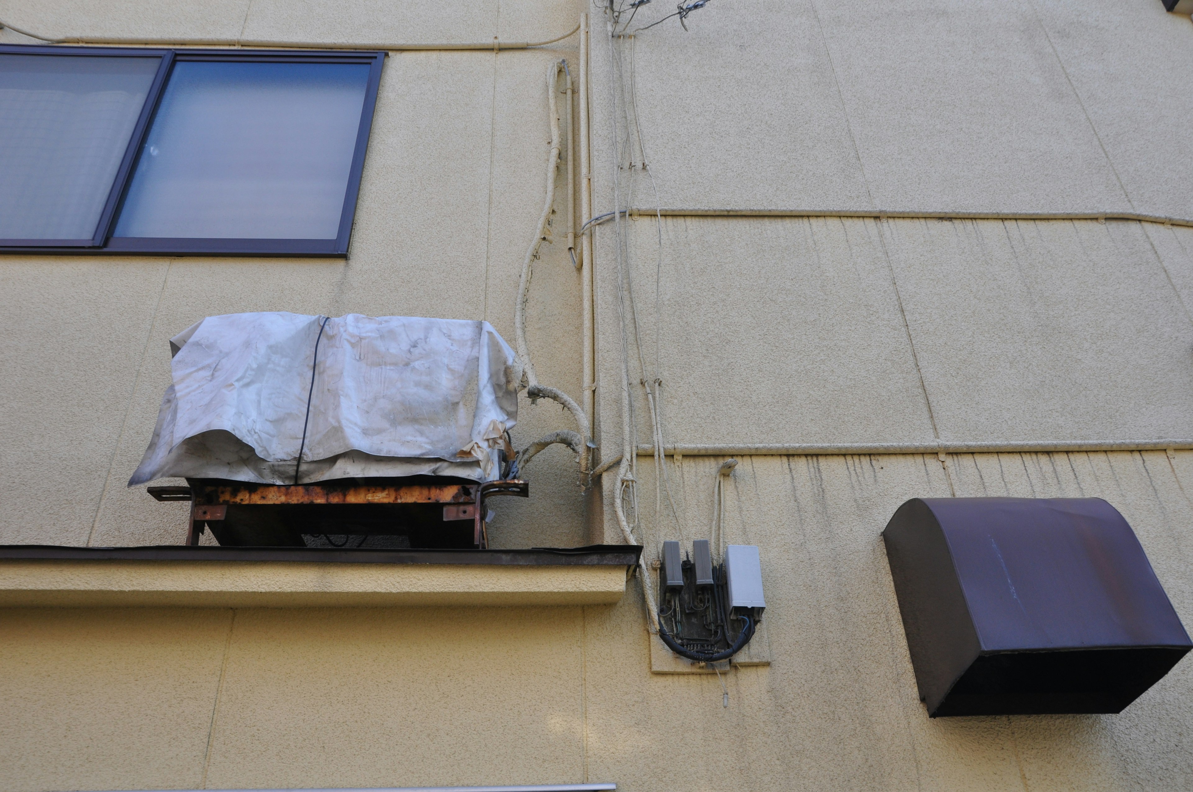 Escena de una unidad de aire acondicionado y una caja eléctrica montadas en la pared exterior de un edificio