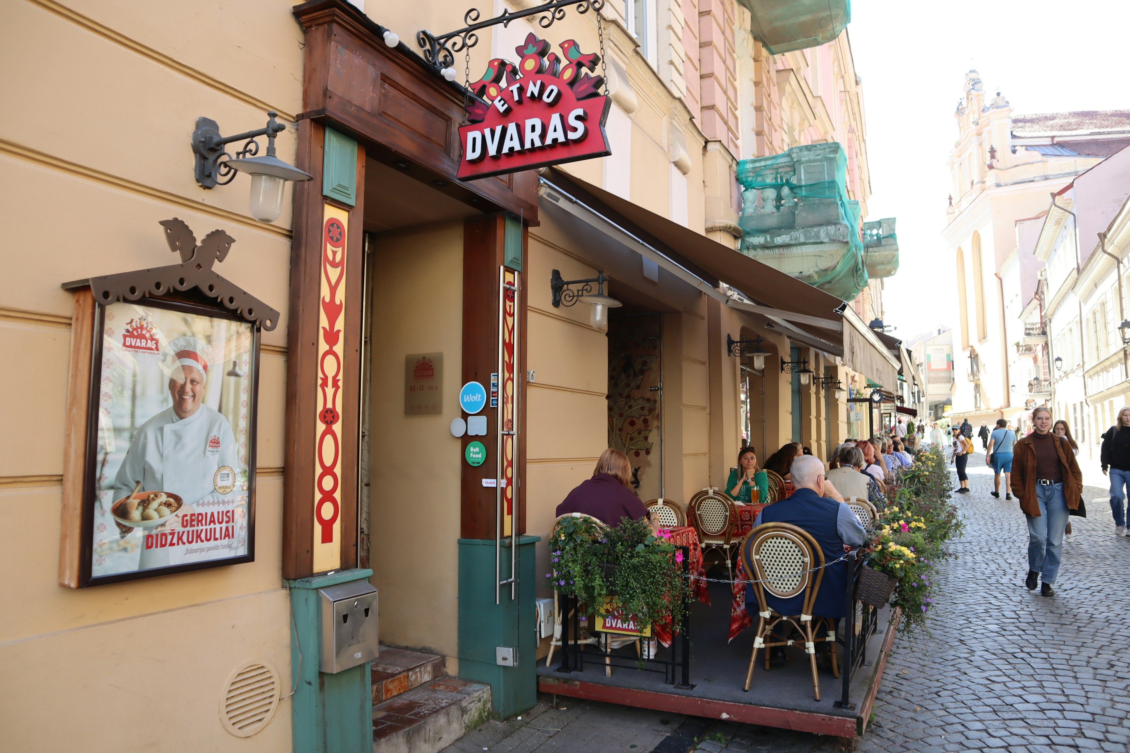 Exterior of DVARAS restaurant in Lithuania with people dining