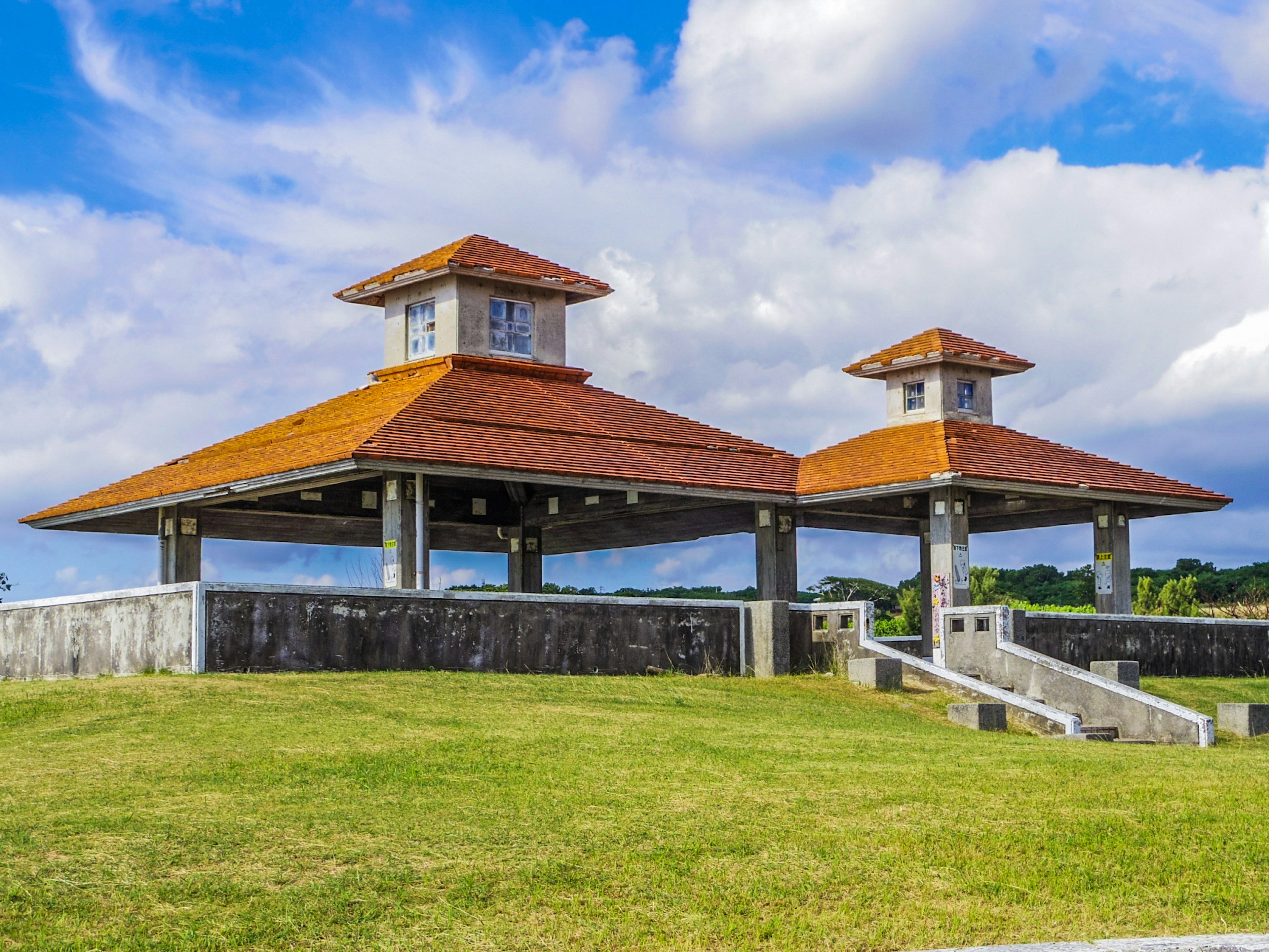 Two roofed pavilions on green grass under a blue sky