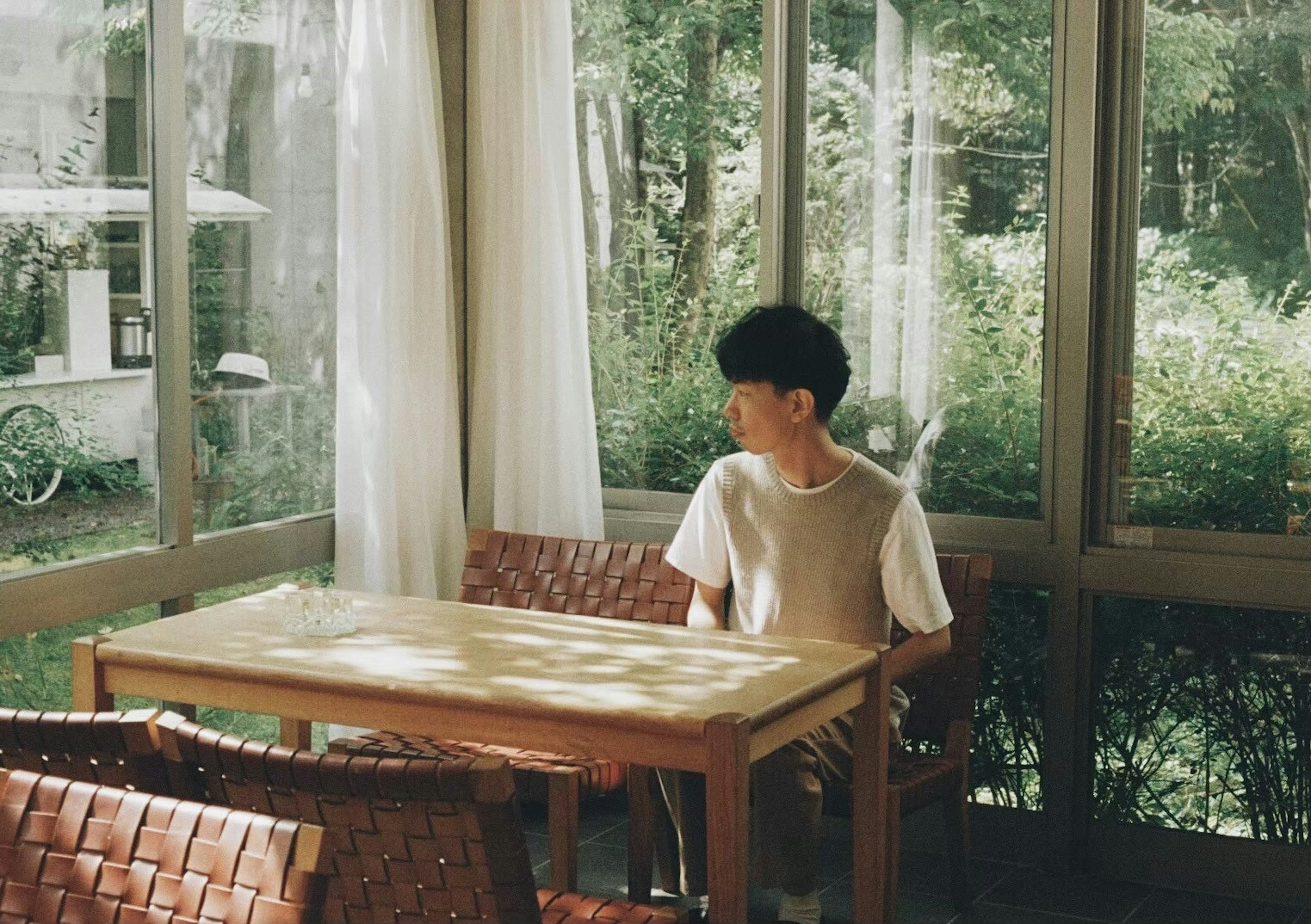 A boy sitting at a table in a room filled with natural light