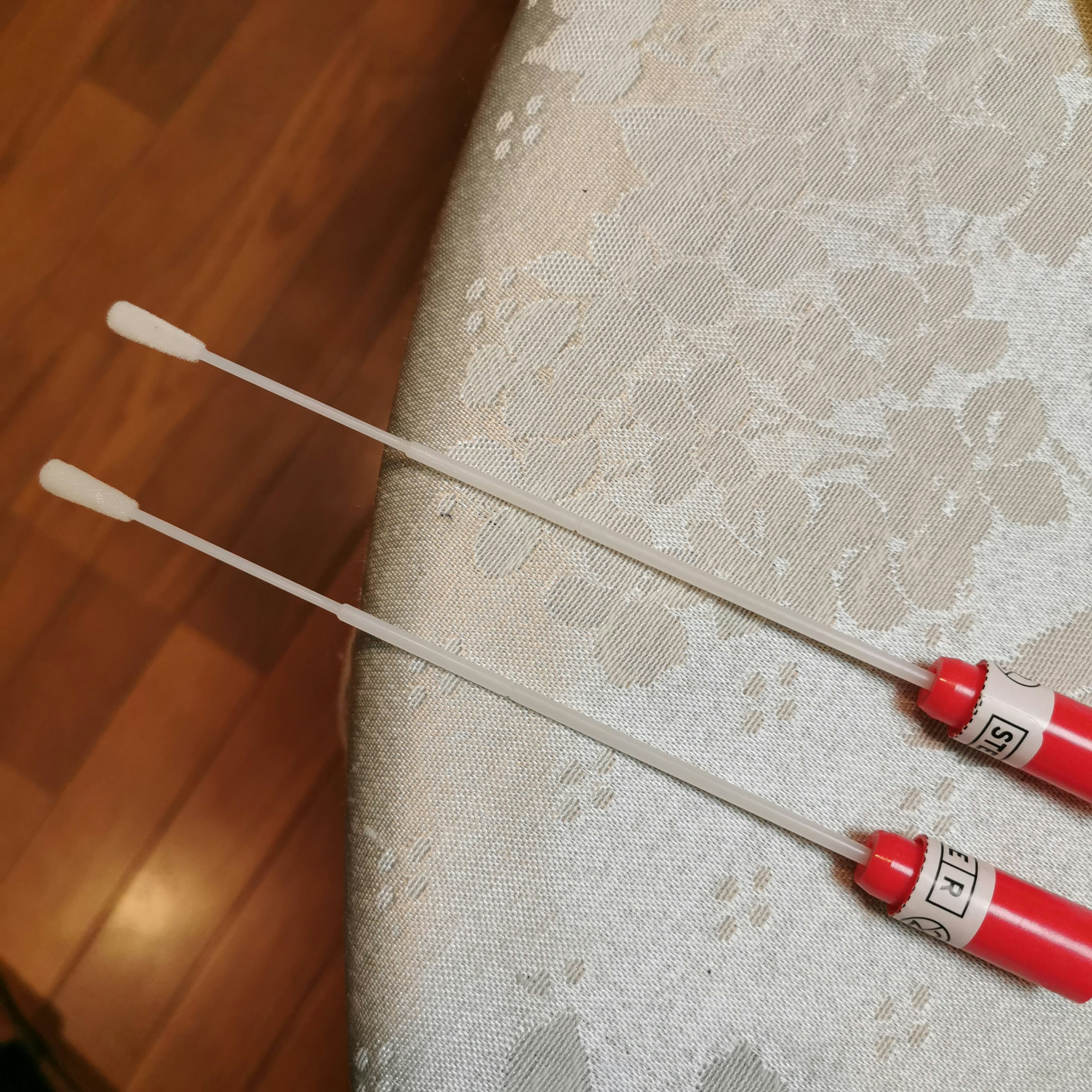 Two long tools with red handles and white tips resting on a patterned surface