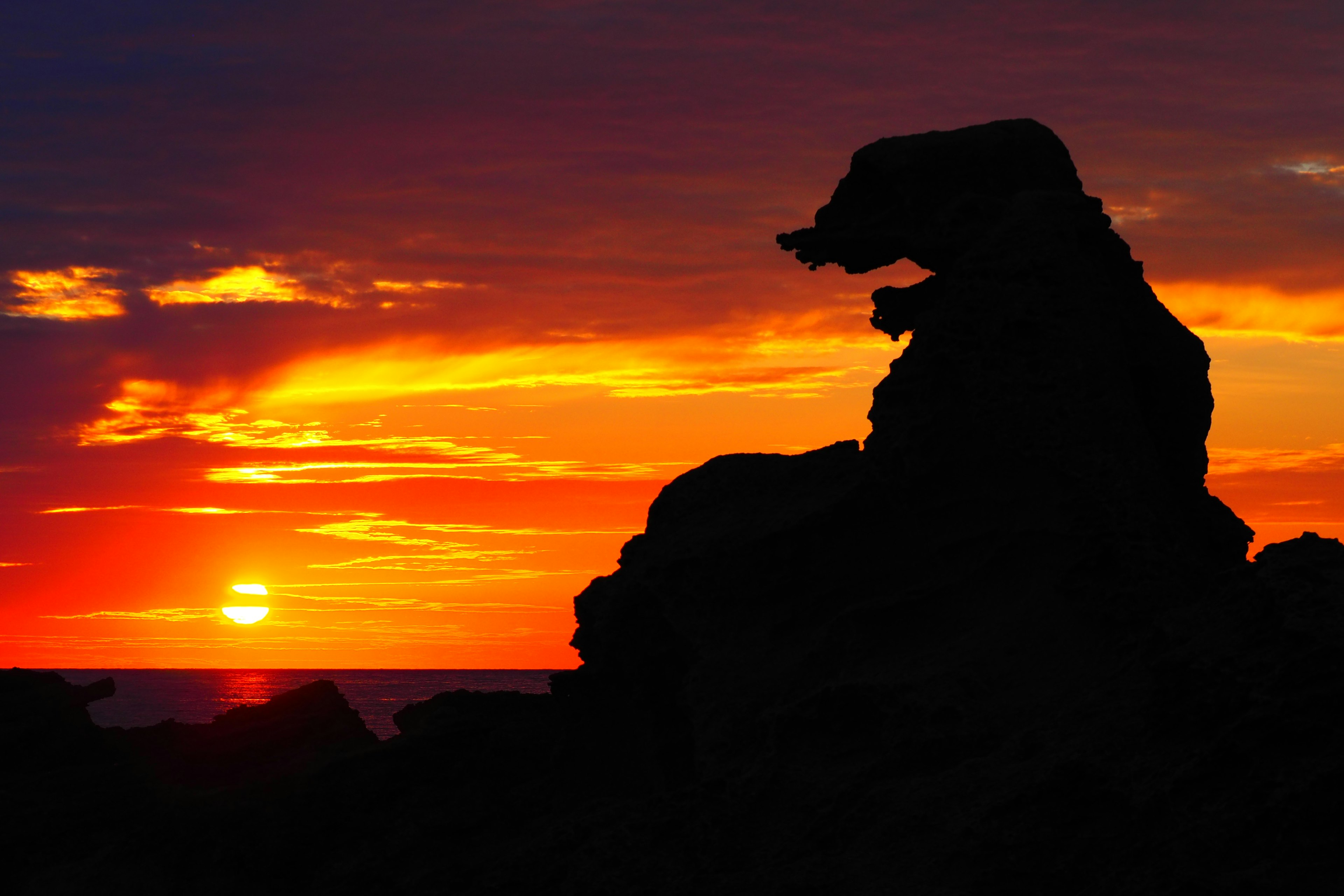 Silhouette of a bear-shaped rock against a vibrant sunset