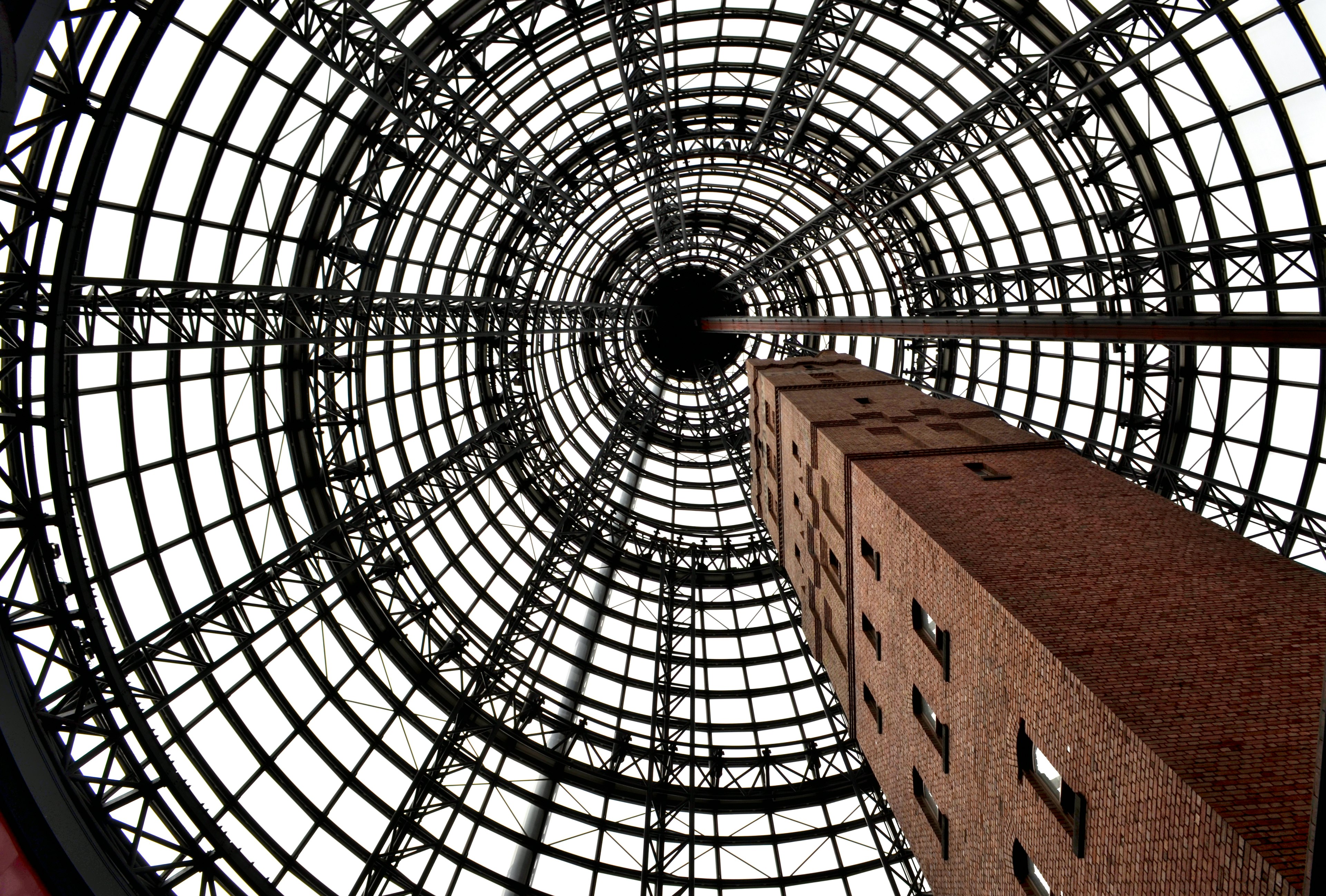 Vista dal basso di un tetto di vetro circolare con una colonna in mattoni