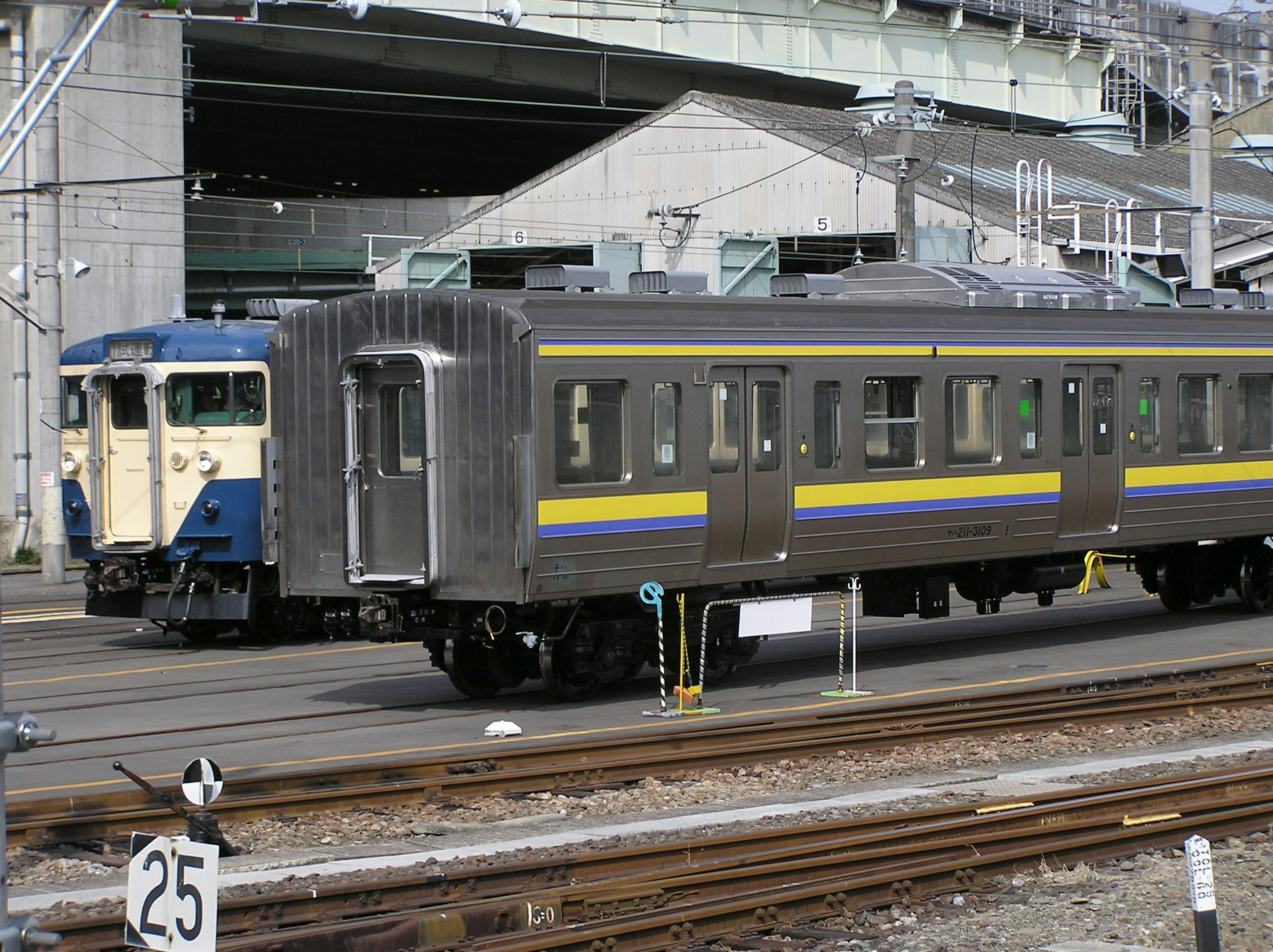 Pemandangan stasiun kereta dengan mobil penumpang berstrip biru dan kuning