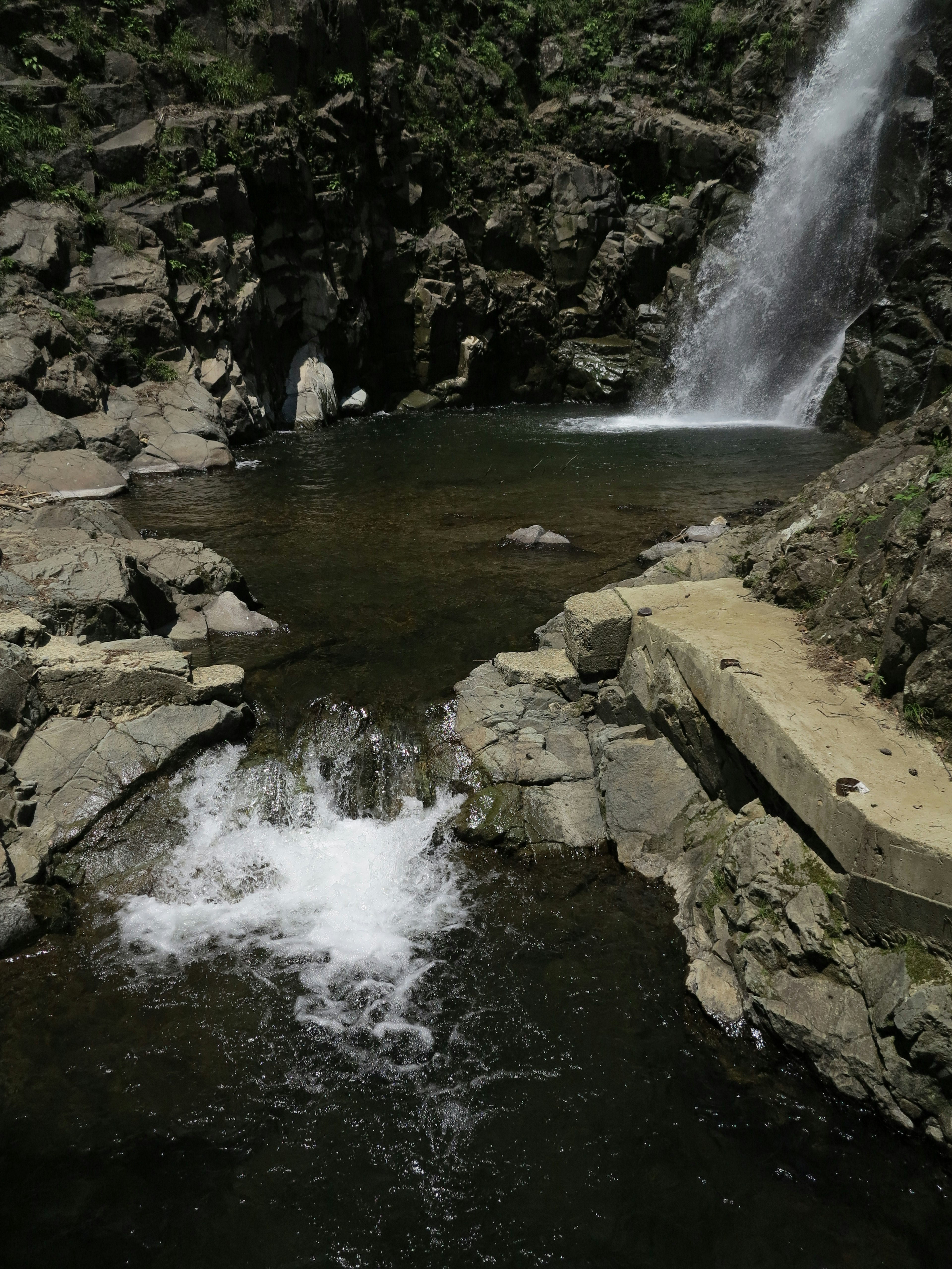 Piscina d'acqua serena circondata da rocce e una cascata