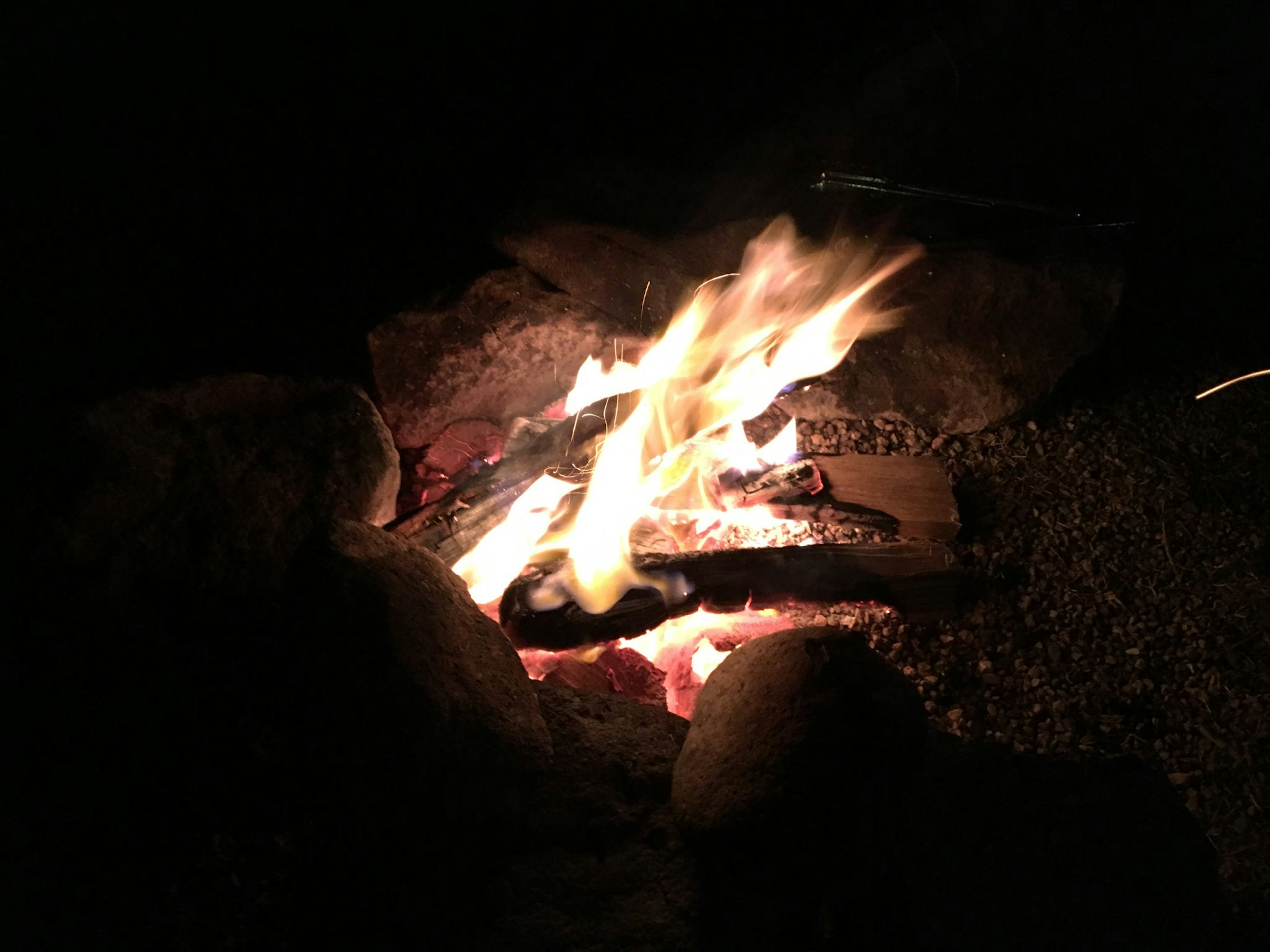 Campfire glowing in the dark surrounded by stones