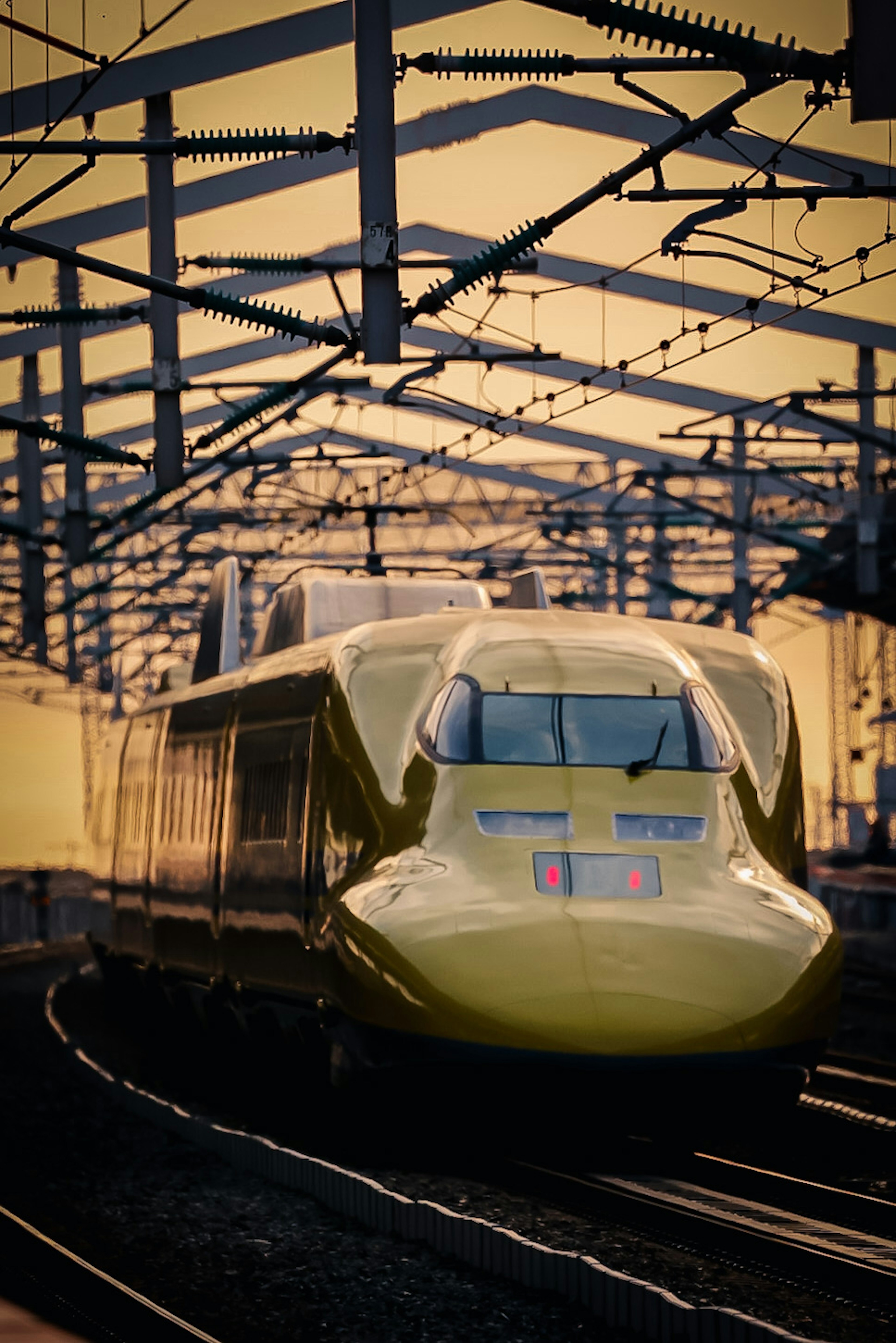 Tàu Shinkansen màu vàng chạy trên nền hoàng hôn