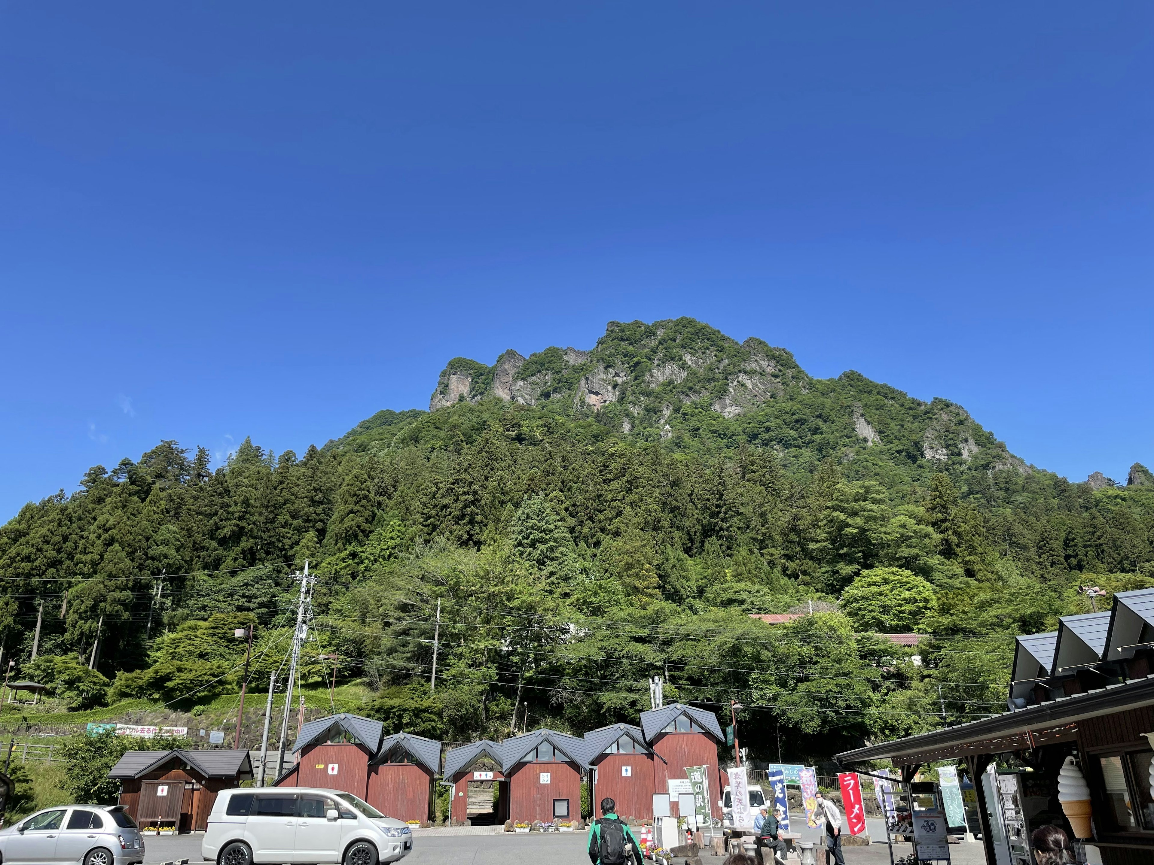 青空の下にある緑豊かな山と赤い小屋群の風景