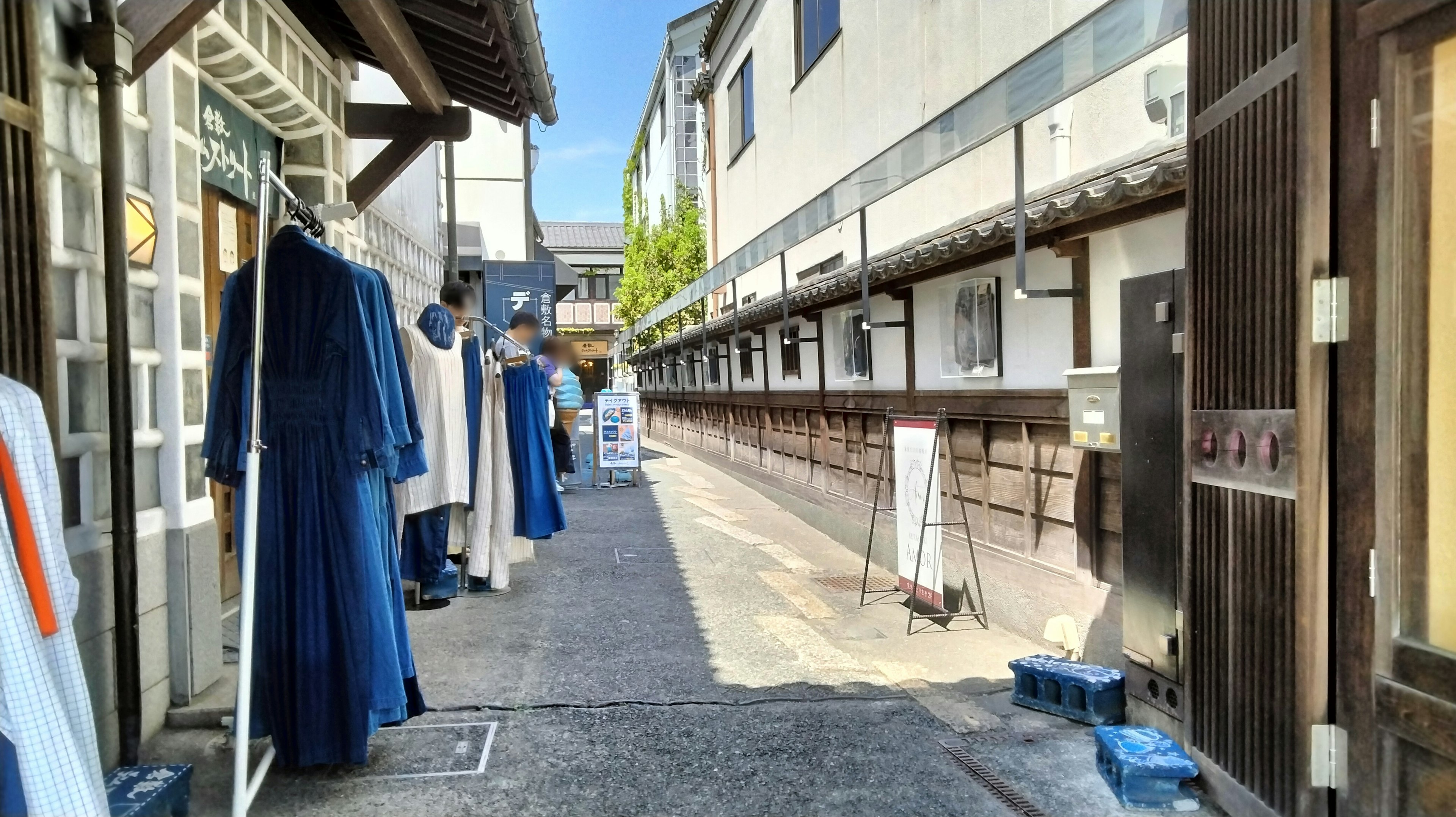 Un callejón estrecho con prendas azules colgadas y edificios tradicionales