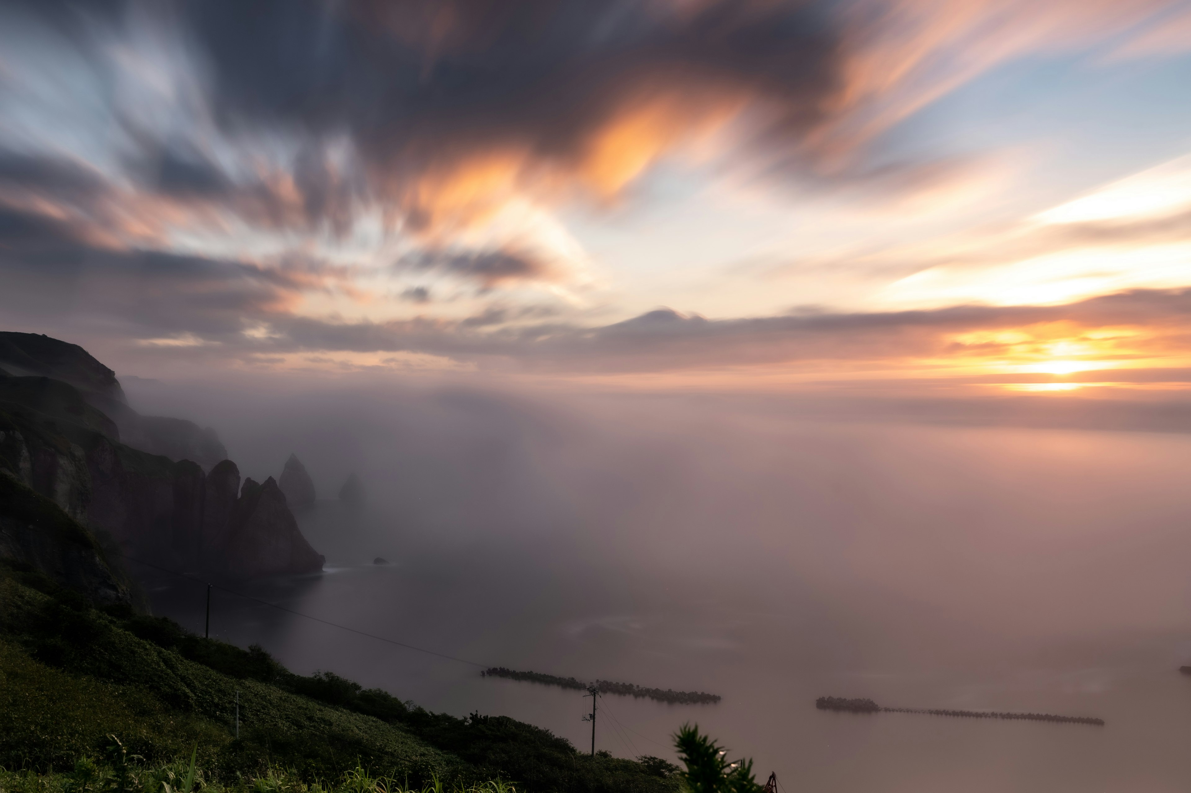 美しい夕焼けの空と霧に包まれた海岸の風景