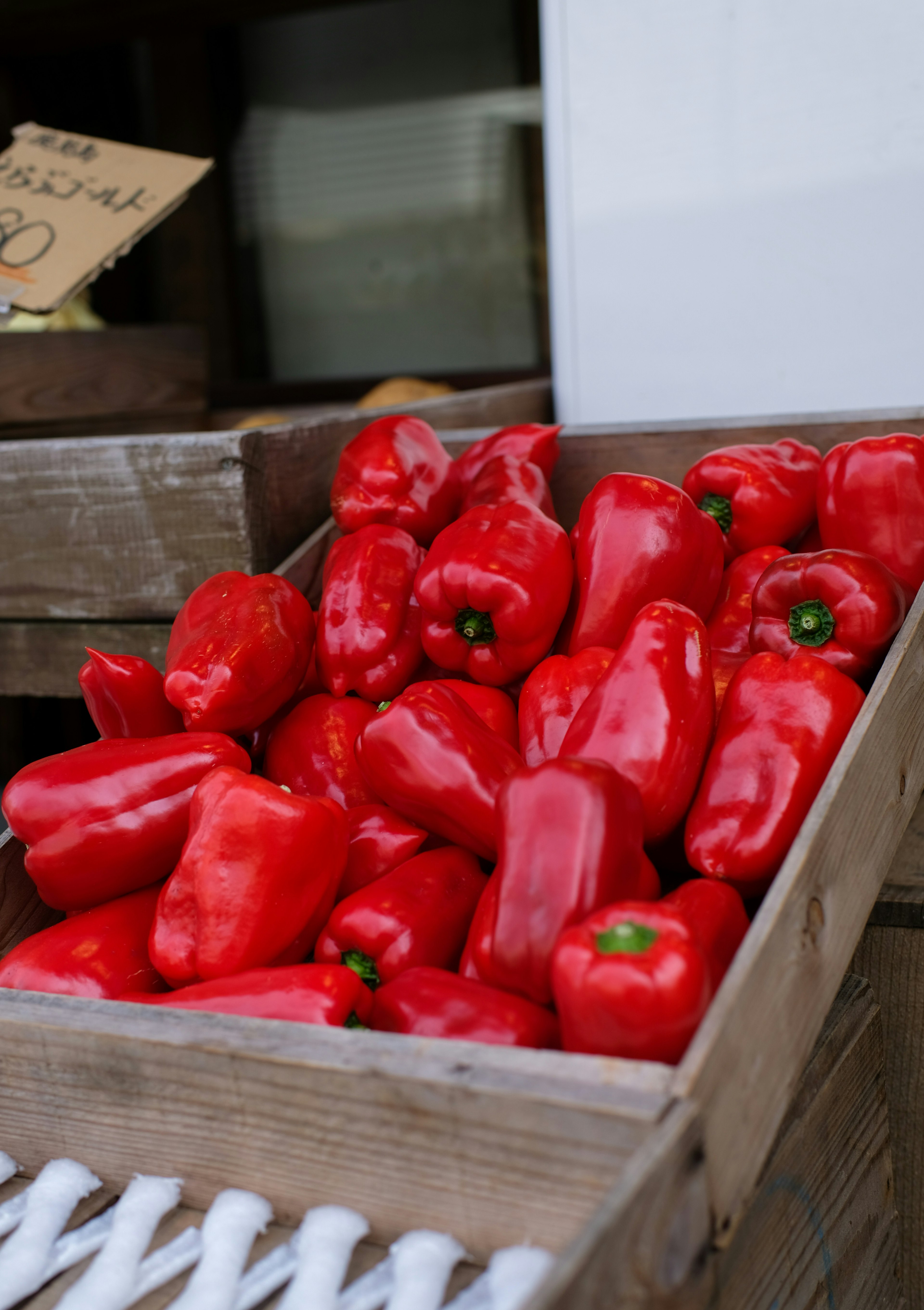 Vibrant red bell peppers arranged in a wooden crate