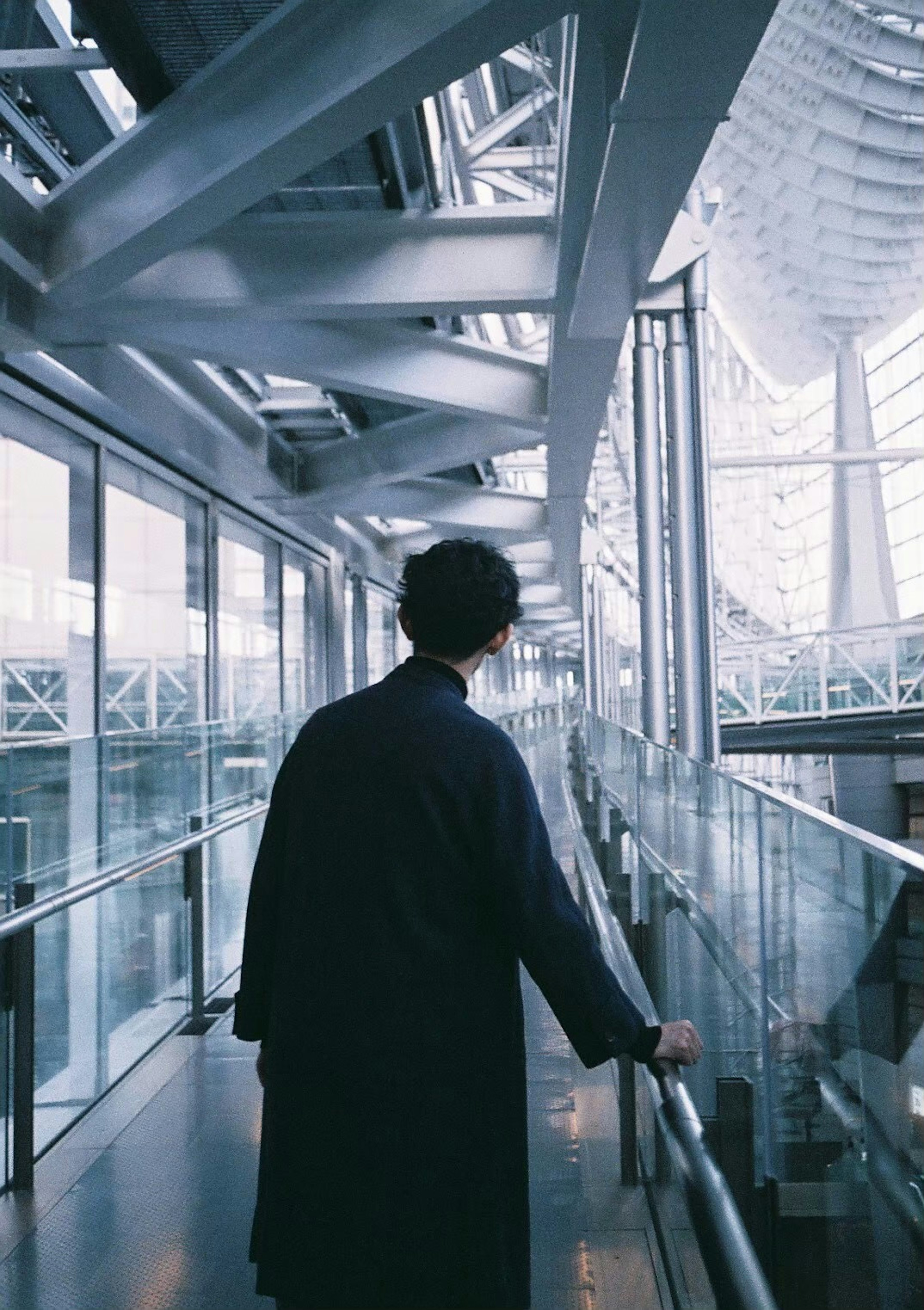 Un homme marchant dans un bâtiment moderne avec une passerelle en verre