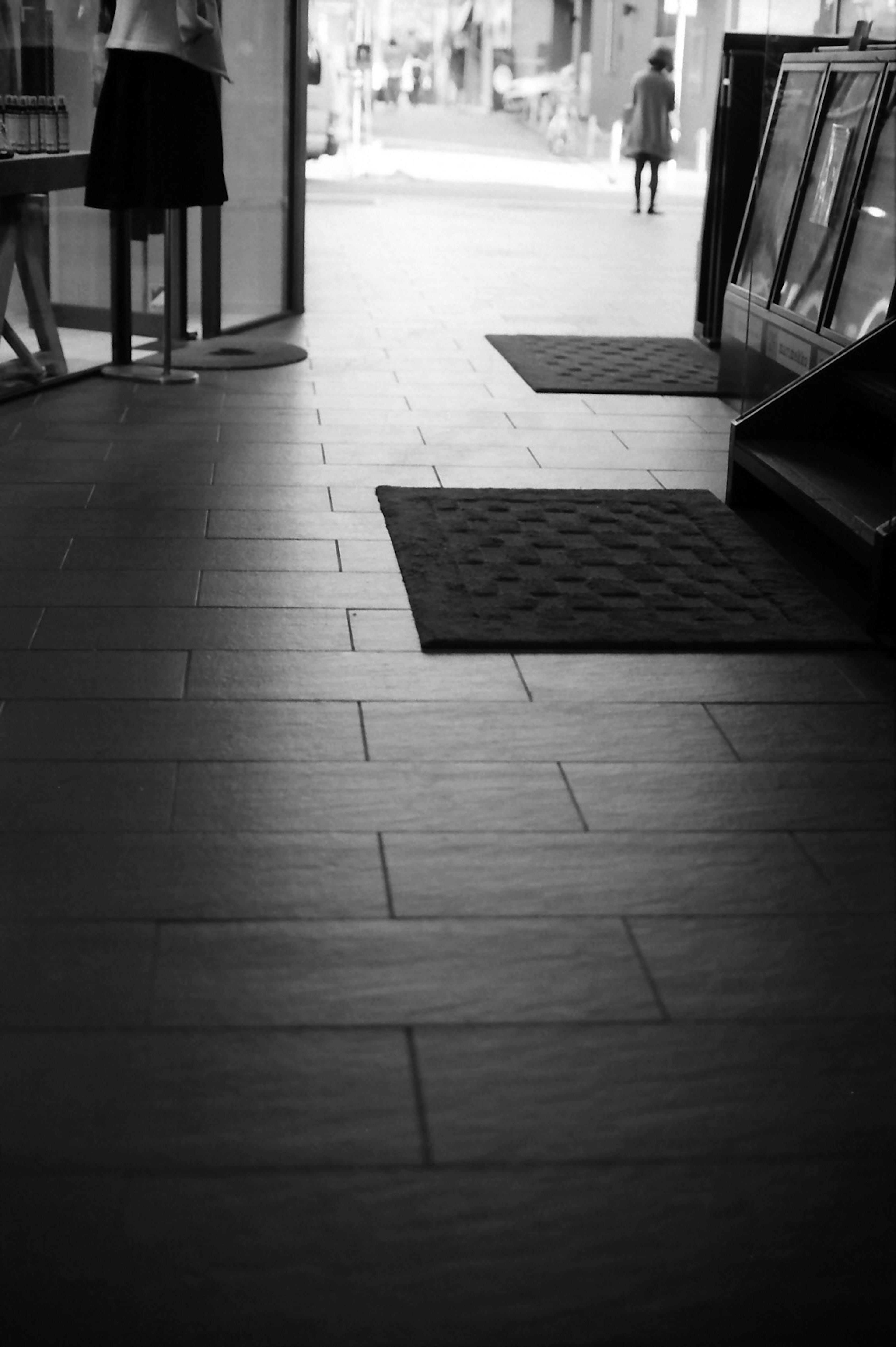 Image en noir et blanc d'un sol intérieur avec des tapis lumière entrant par une porte