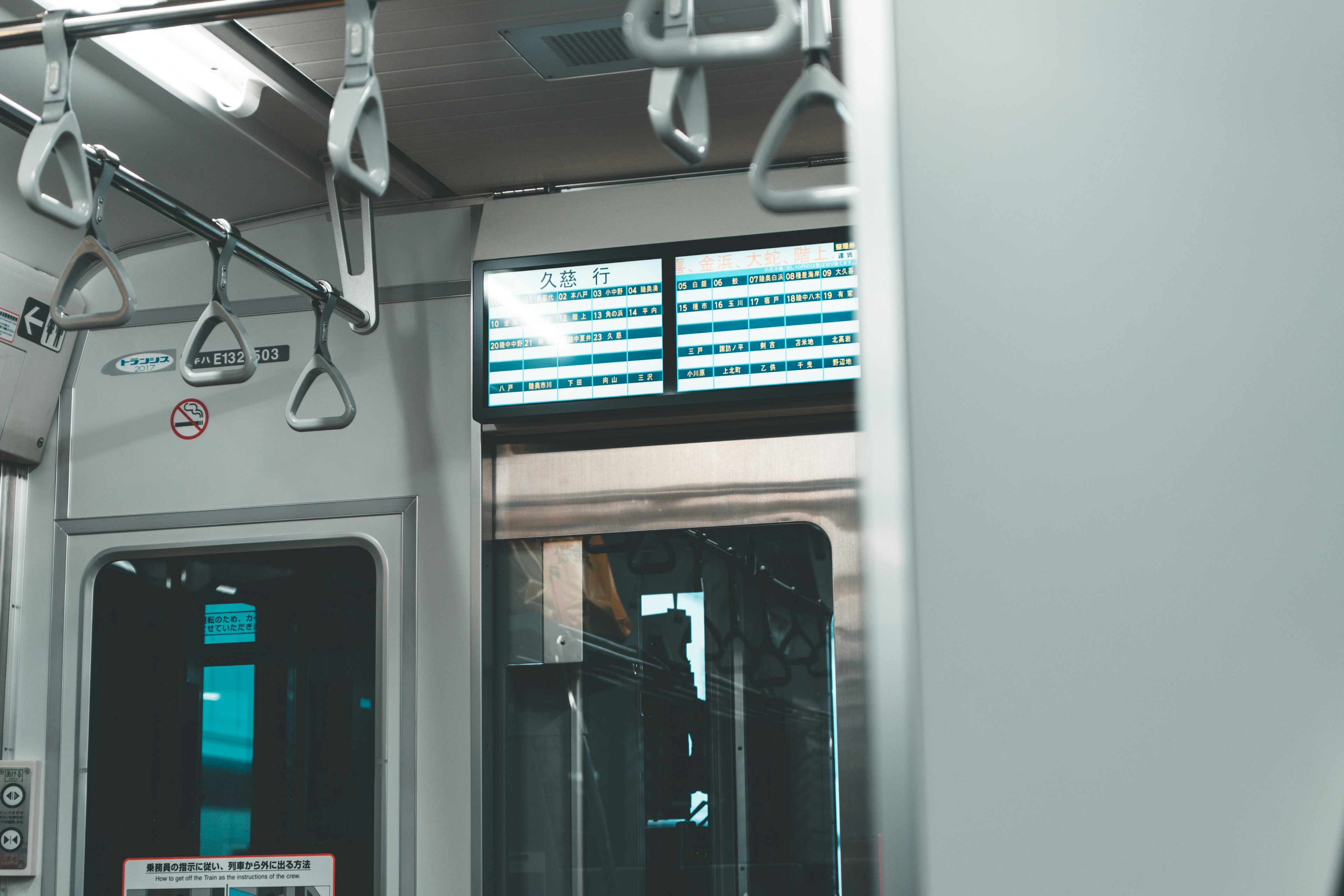 Interior de un tren con pasamanos y una pantalla digital