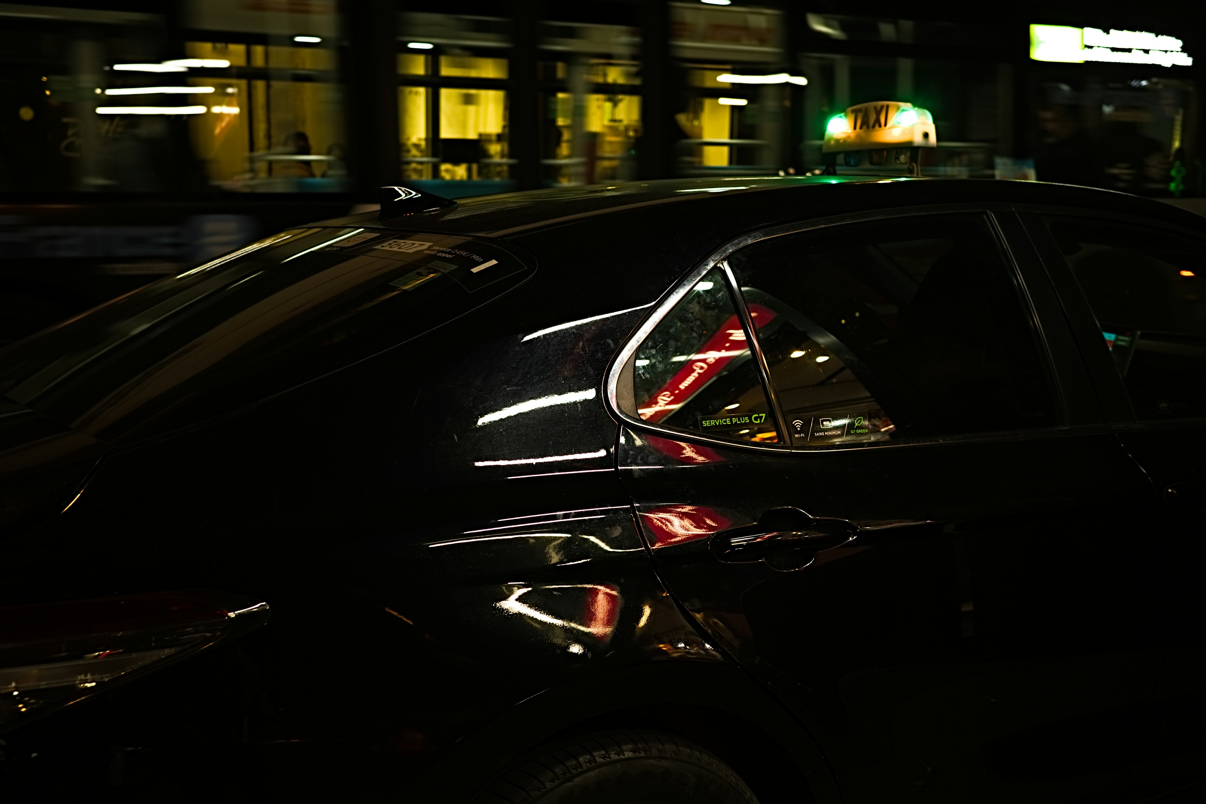 Côté d'une voiture noire reflétant les lumières de la ville la nuit