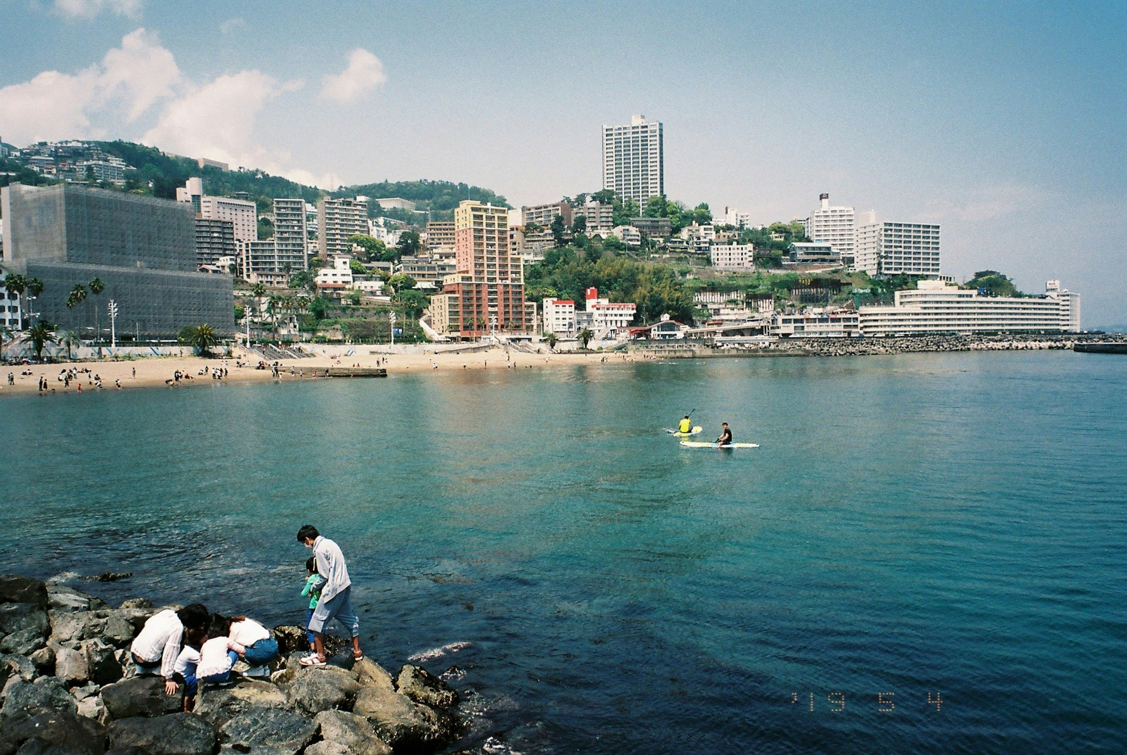 海岸城市景观，有人在岩石上工作和划皮艇