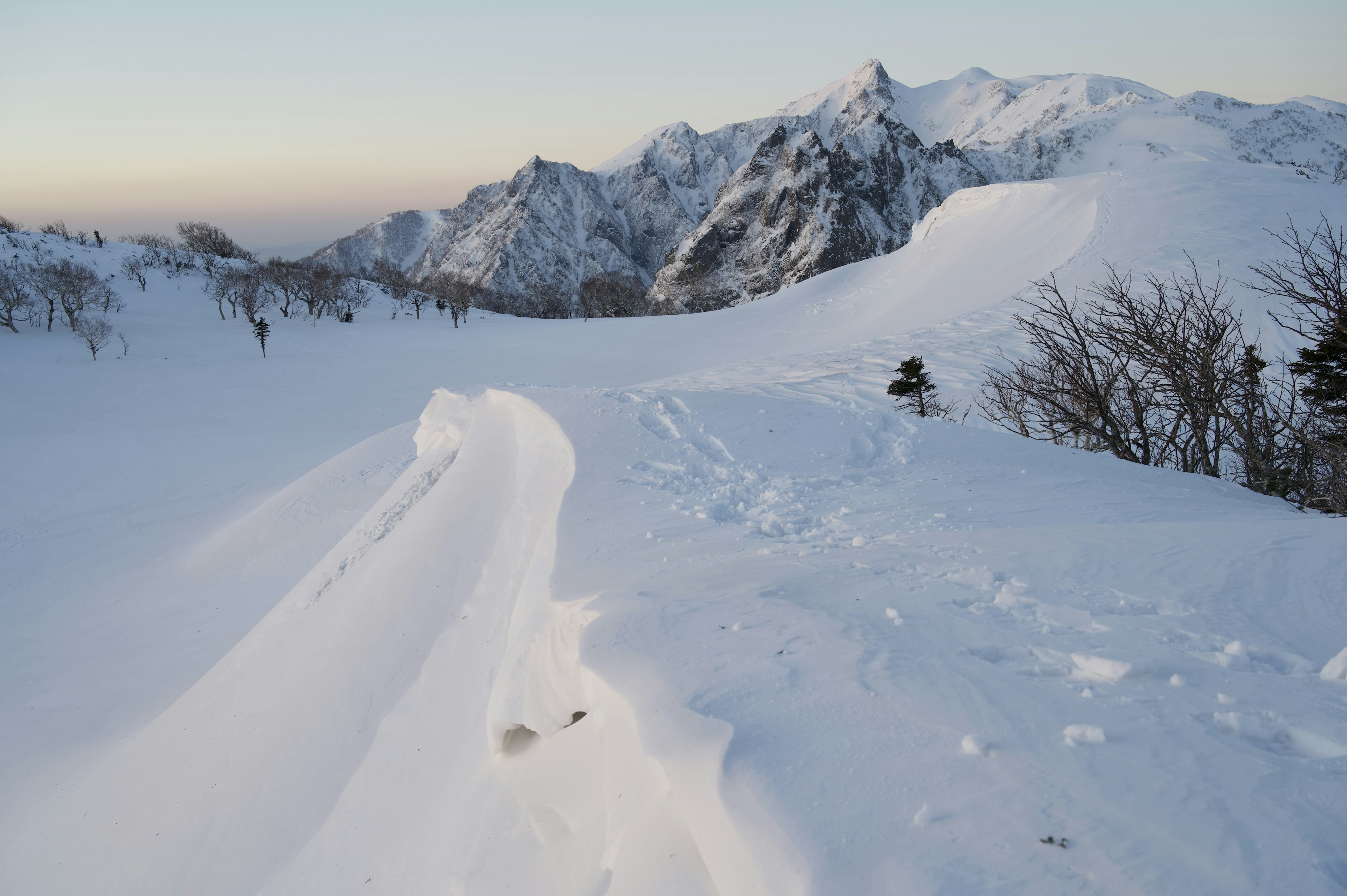 Paisaje montañoso cubierto de nieve con huellas de senderismo