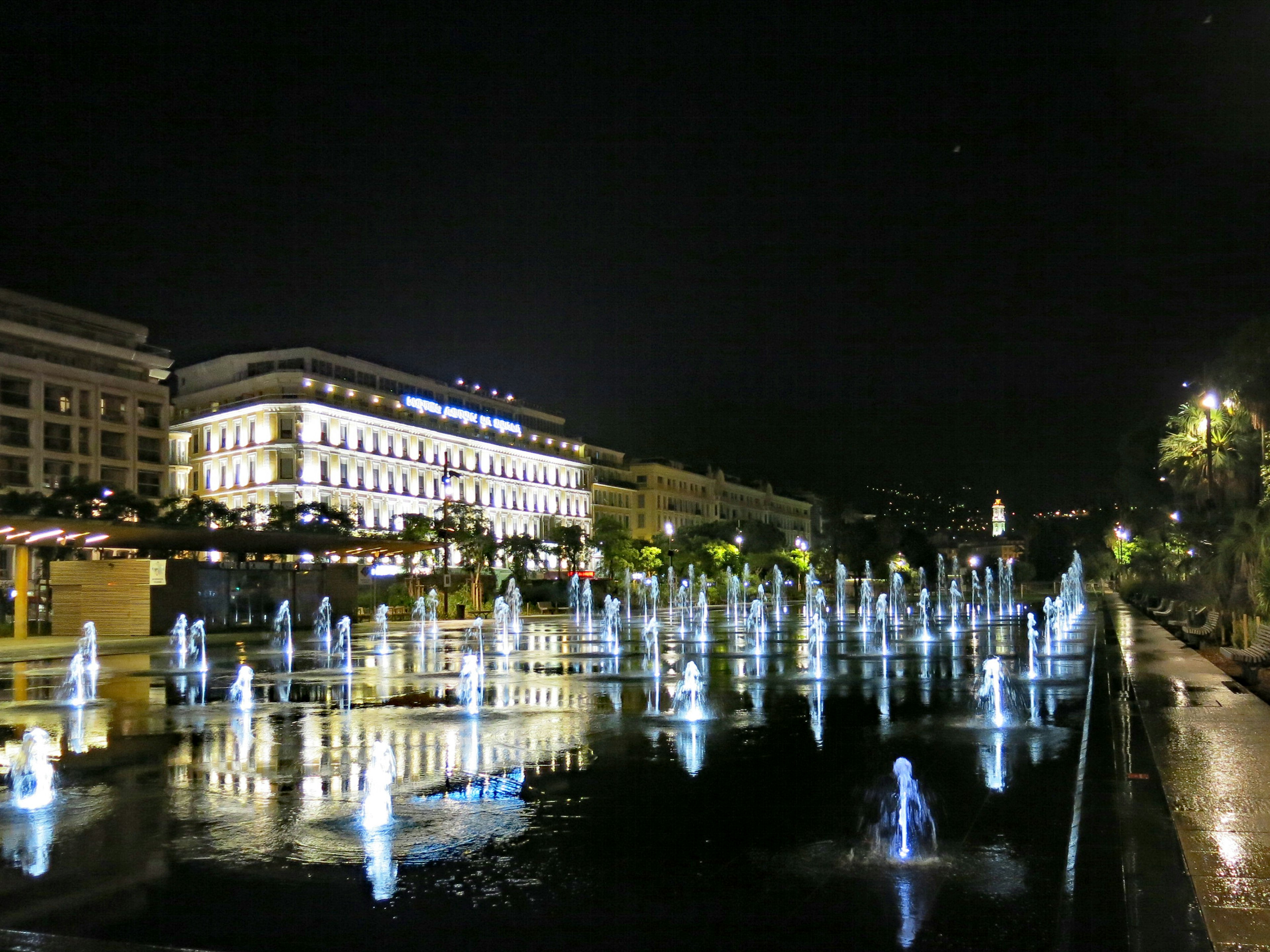 Paesaggio urbano notturno con fontane illuminate e riflessi