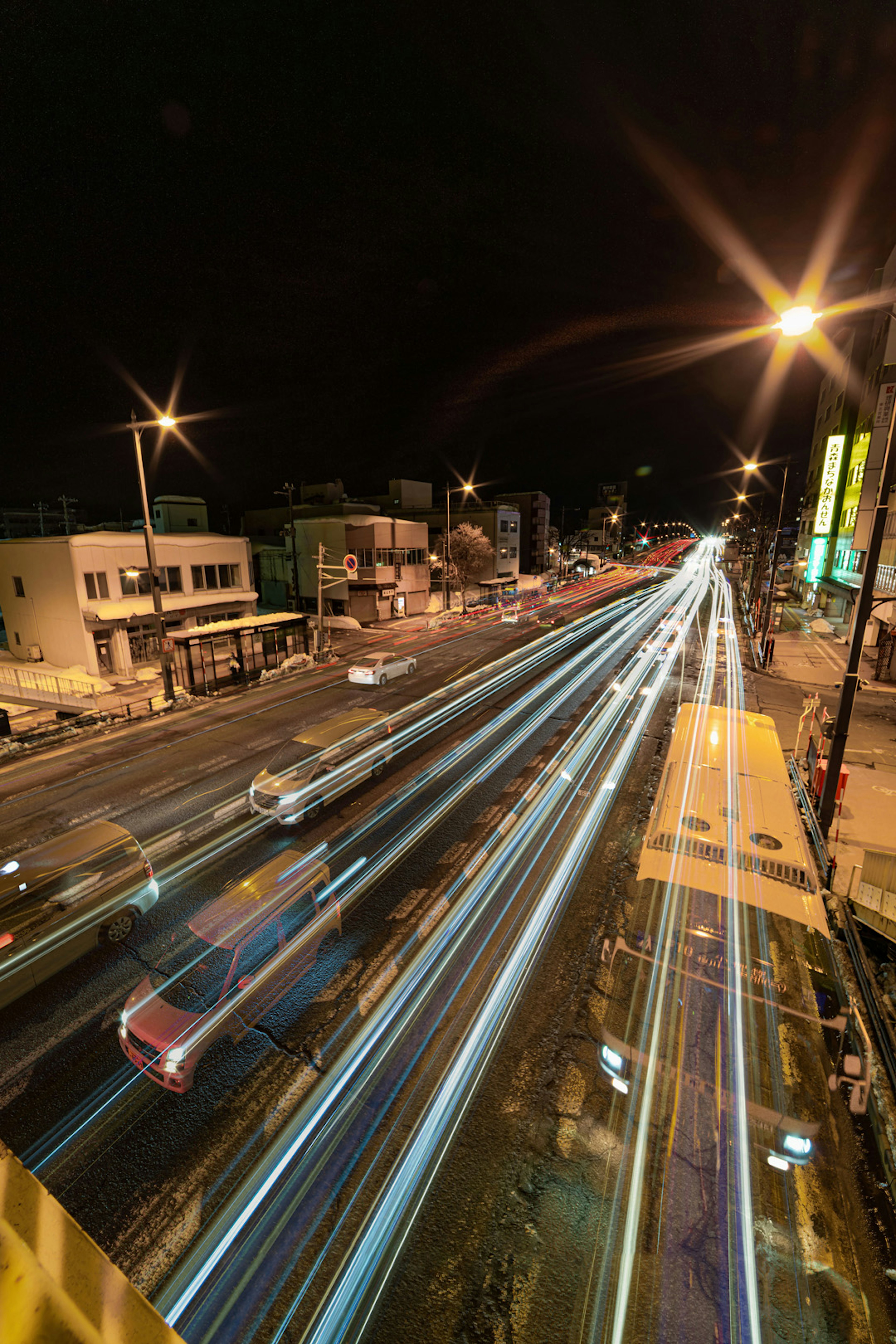 Vue nocturne d'une intersection urbaine avec des traînées de lumière des voitures