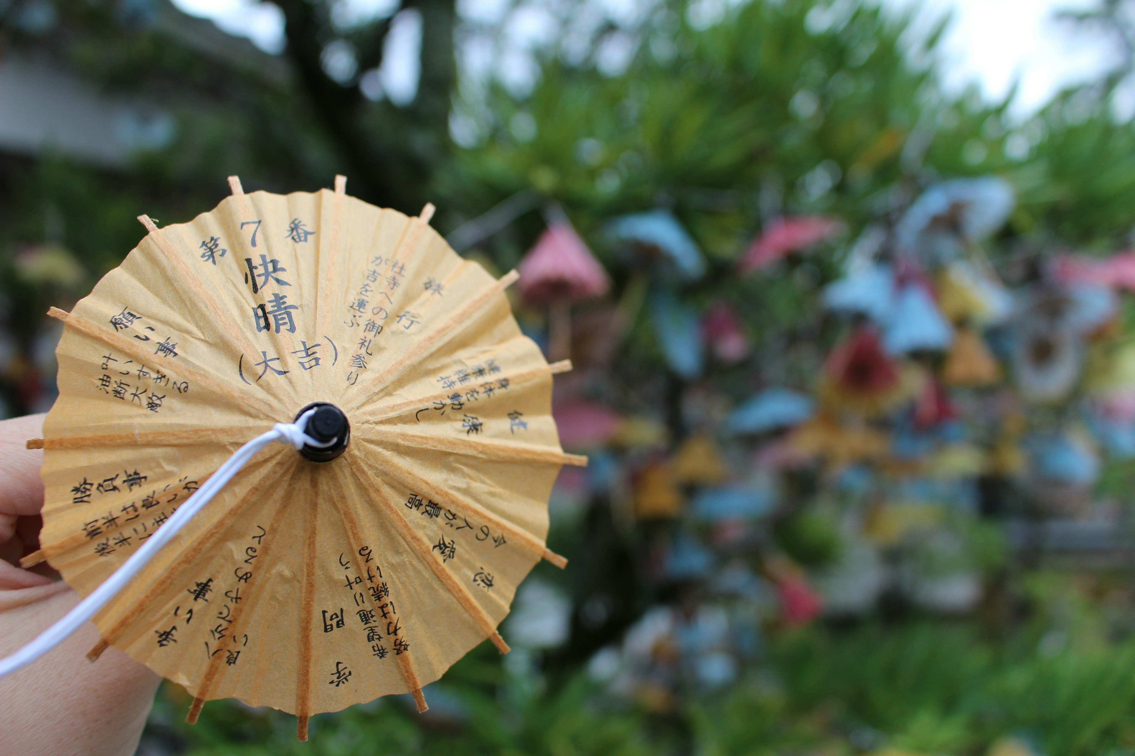 A small yellow umbrella held in hand with colorful decorations in the background