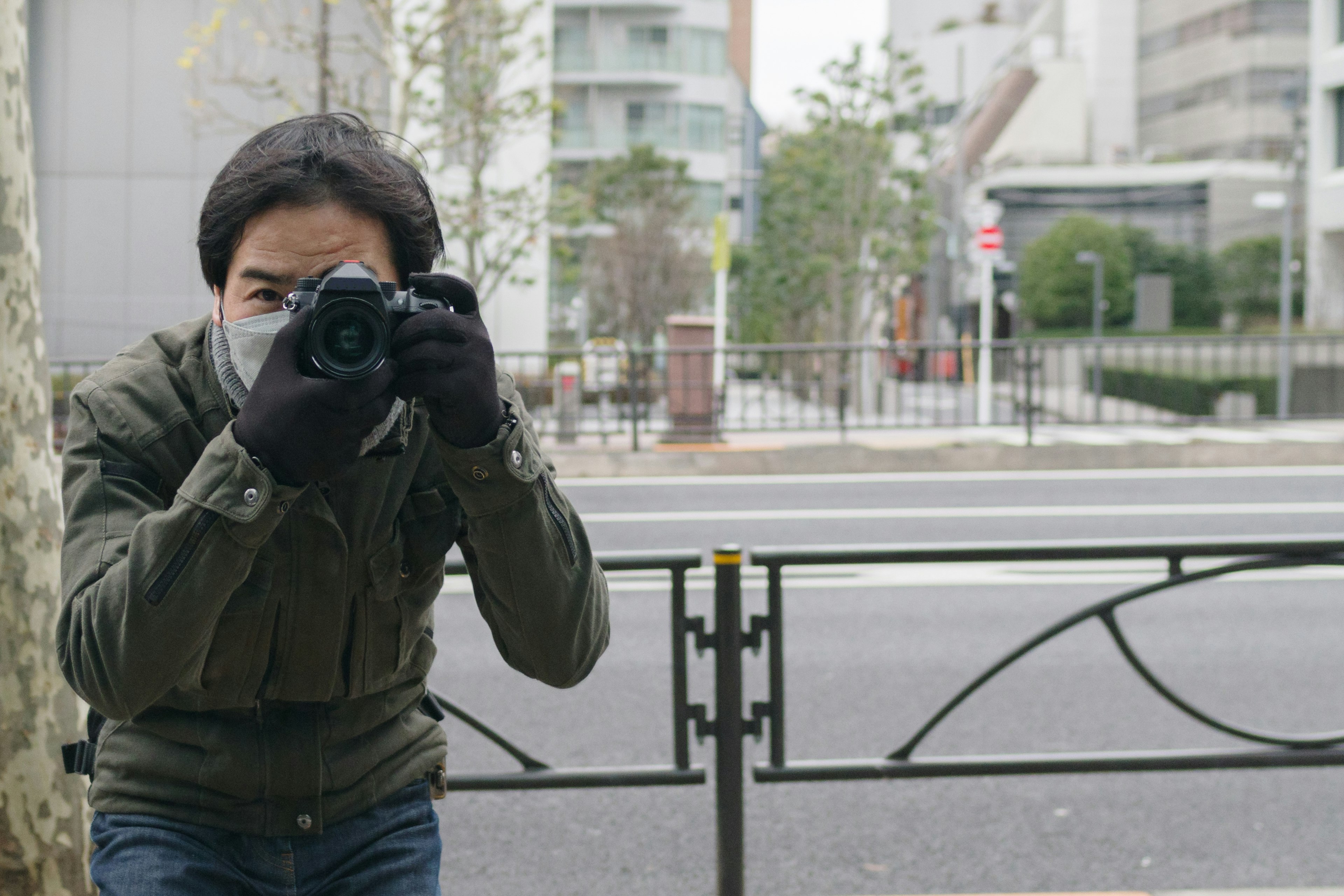 A man holding a camera while taking pictures in an urban setting