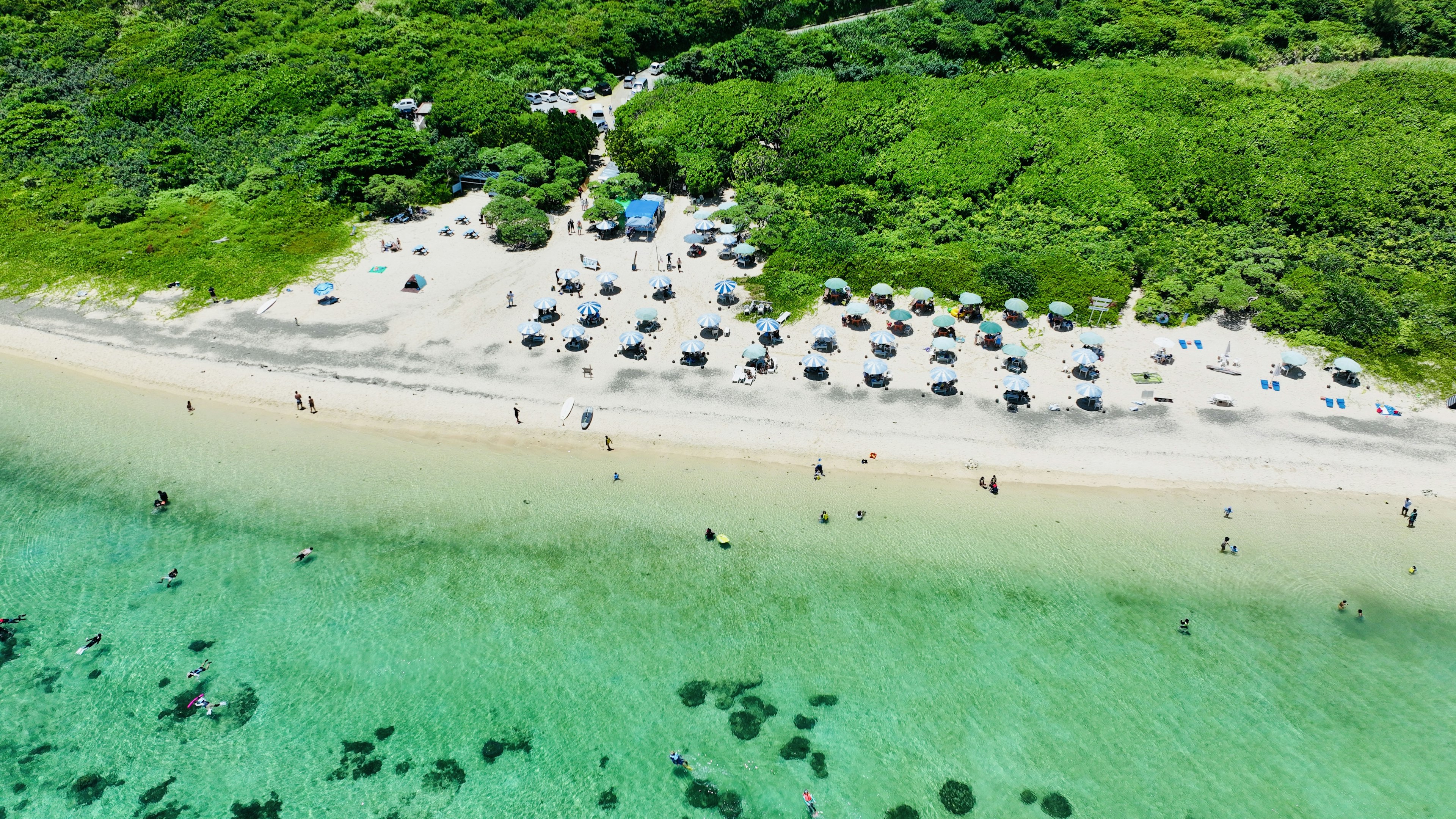 Strandszene mit Sonnenschirmen auf weißem Sand und klarem Wasser