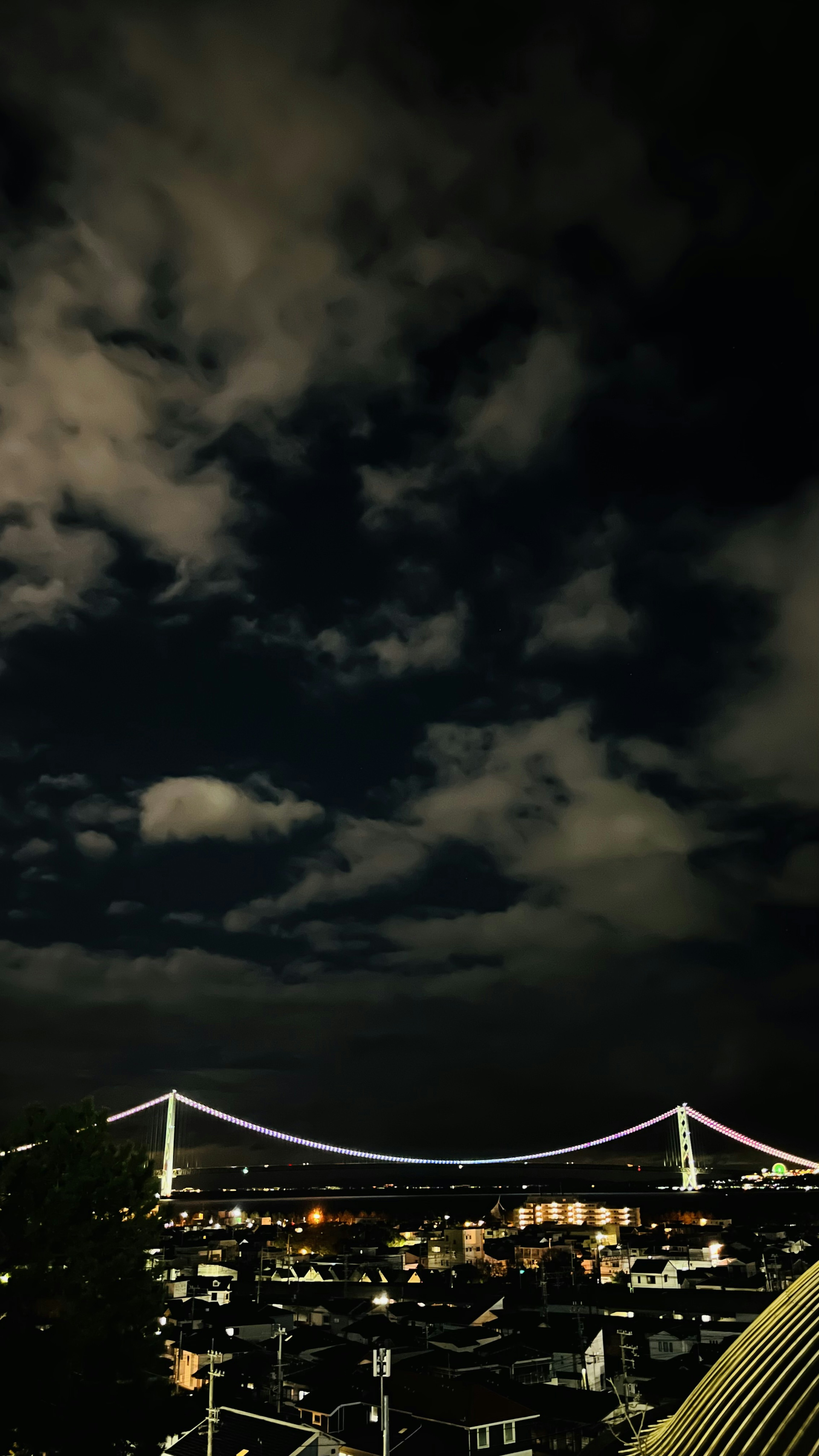 Cielo notturno con nuvole e vista su un ponte illuminato