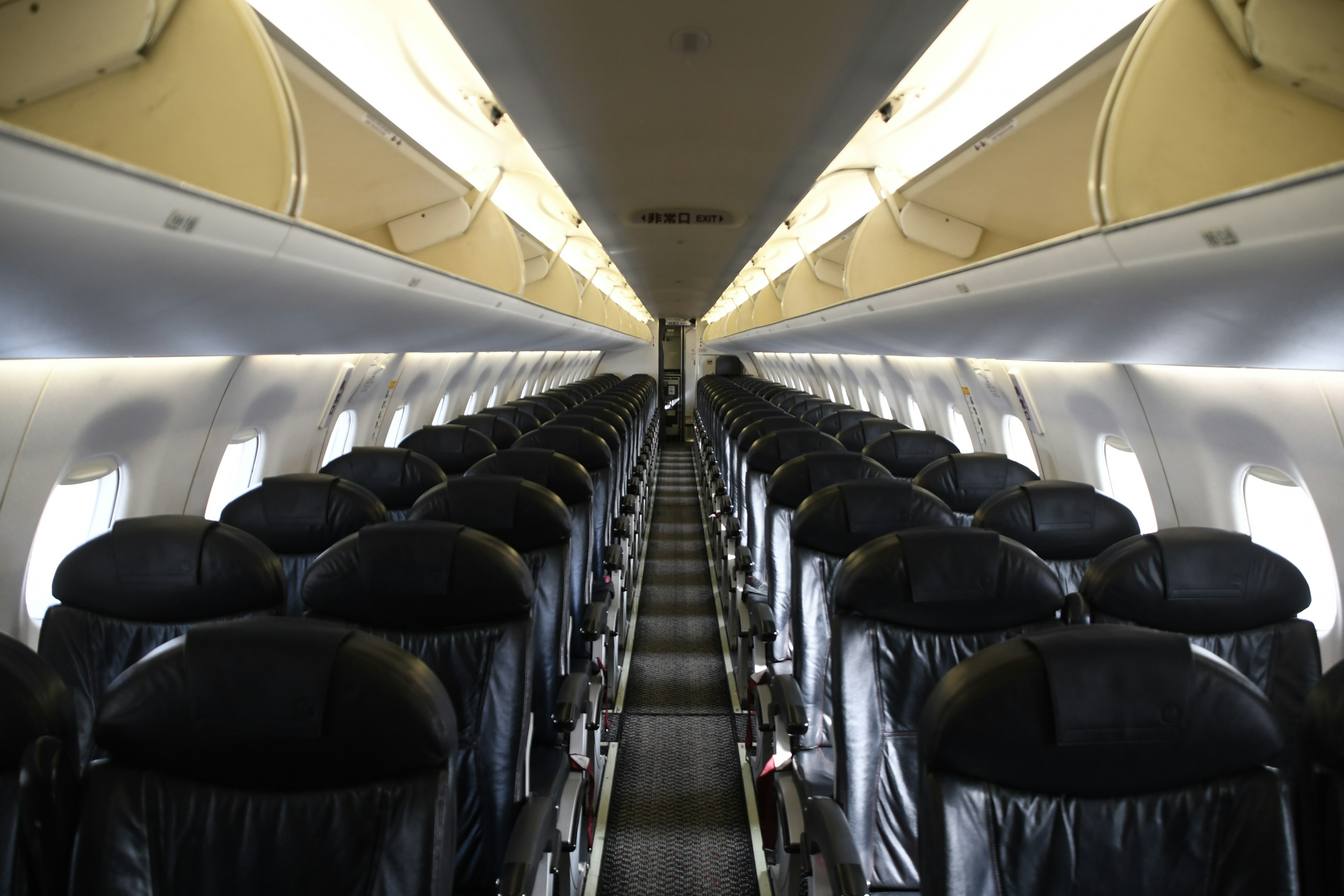 Interior of an airplane featuring rows of black leather seats