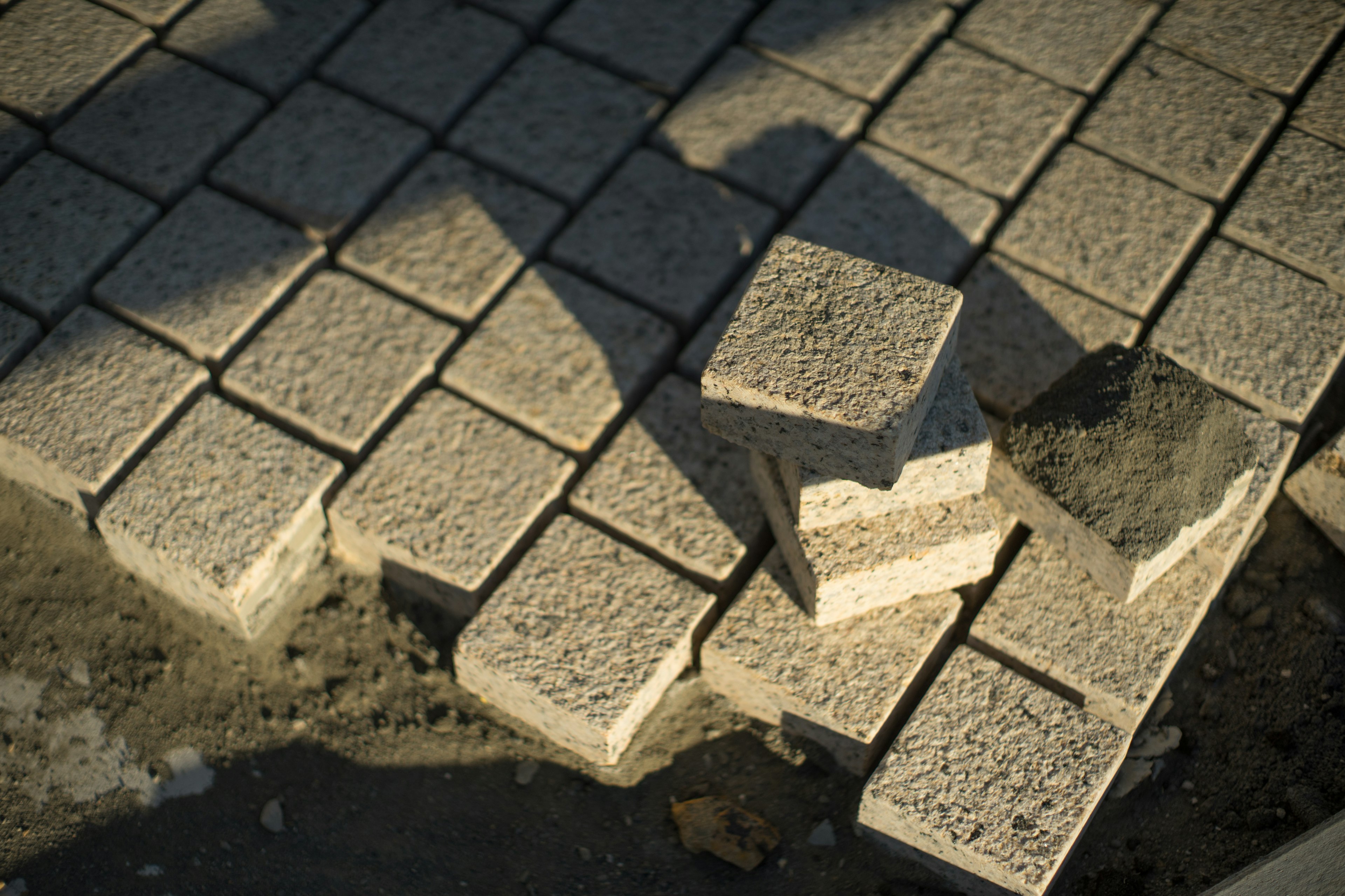 Blocchi di pietra pavimentati disposti sul terreno con ombre