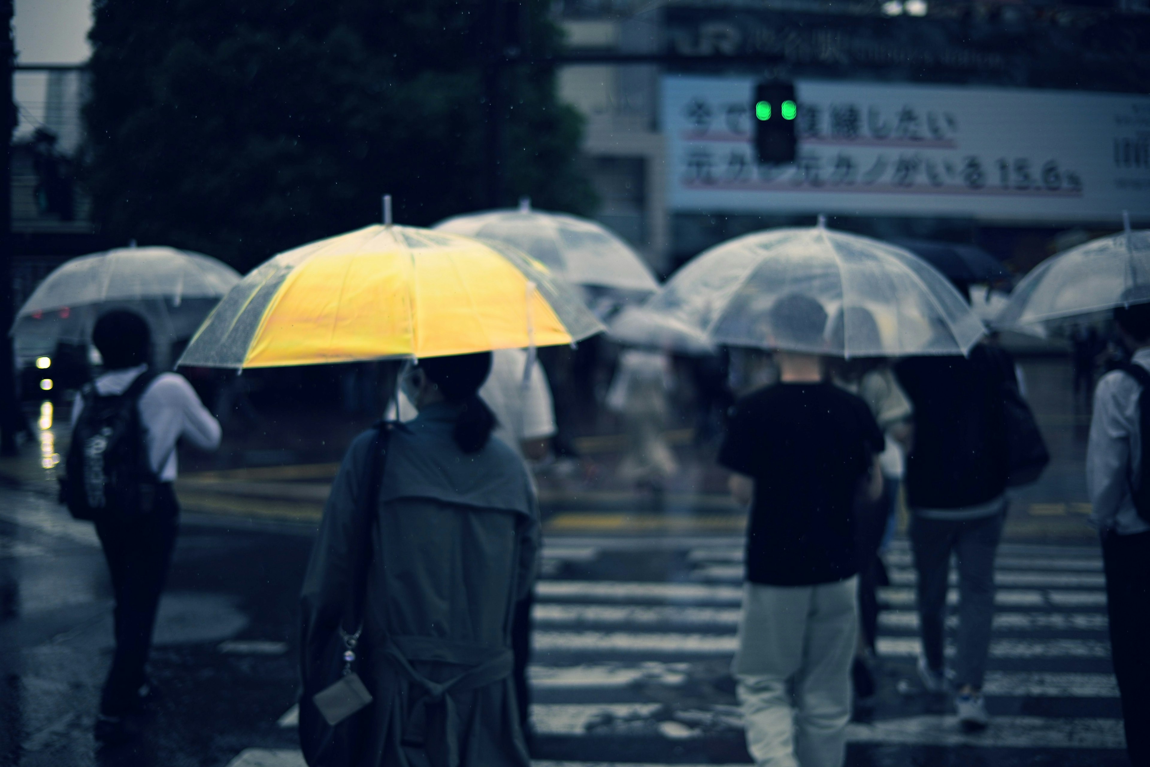 人在雨中走，手持黃色雨傘