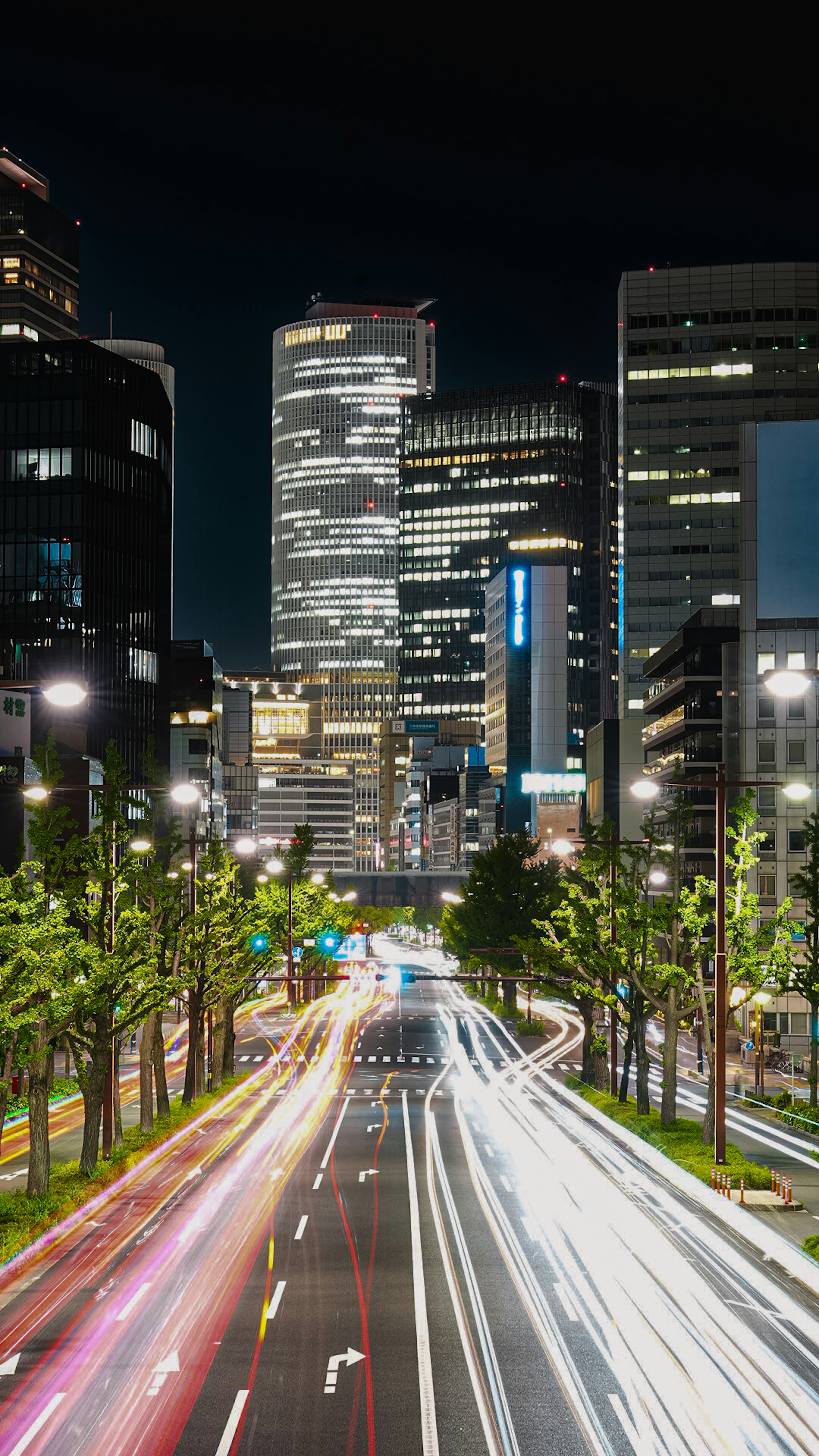 Paisaje urbano nocturno con rascacielos y estelas de luz de coches