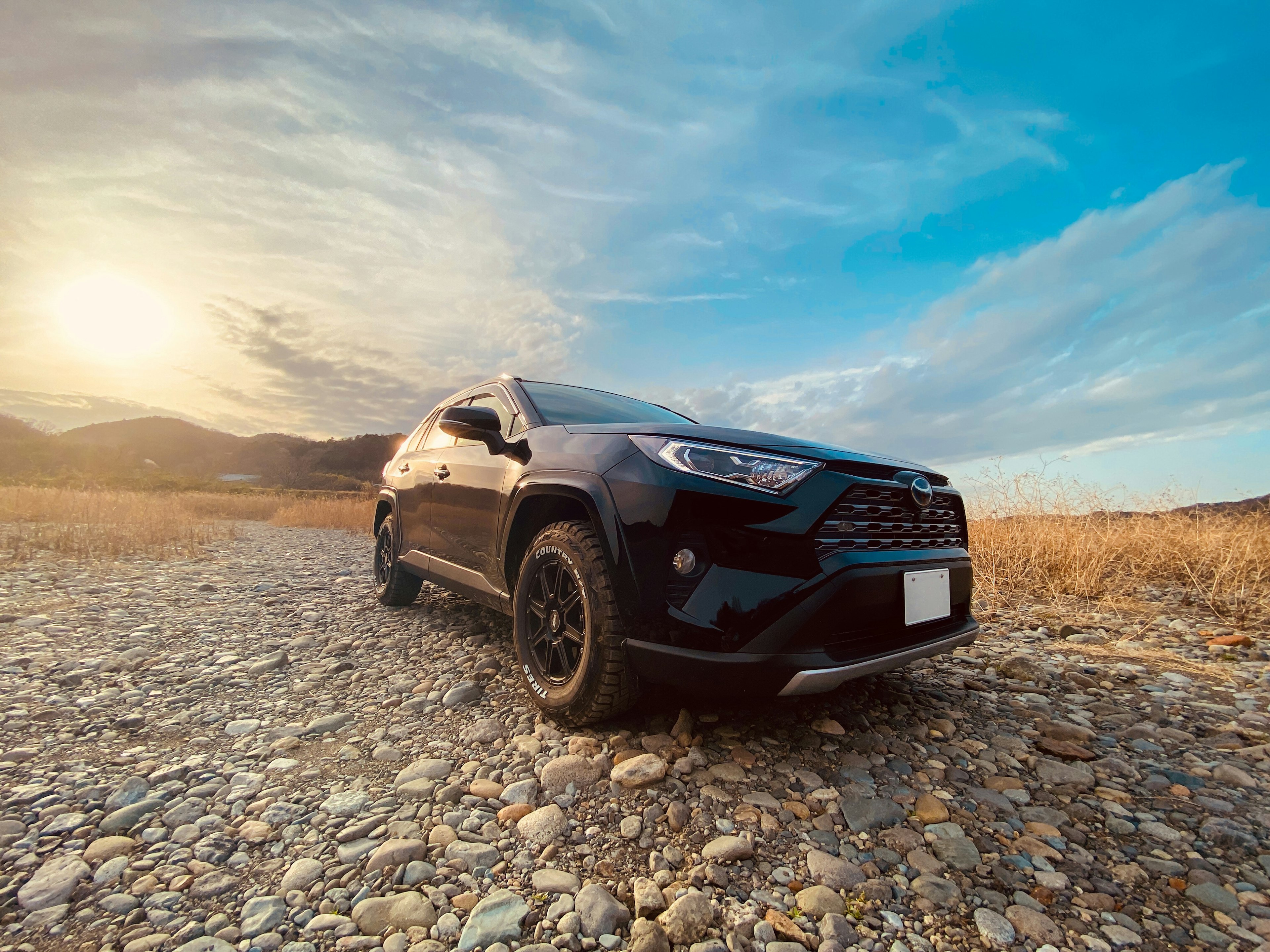 Schwarzer SUV unter einem Sonnenuntergangshimmel geparkt