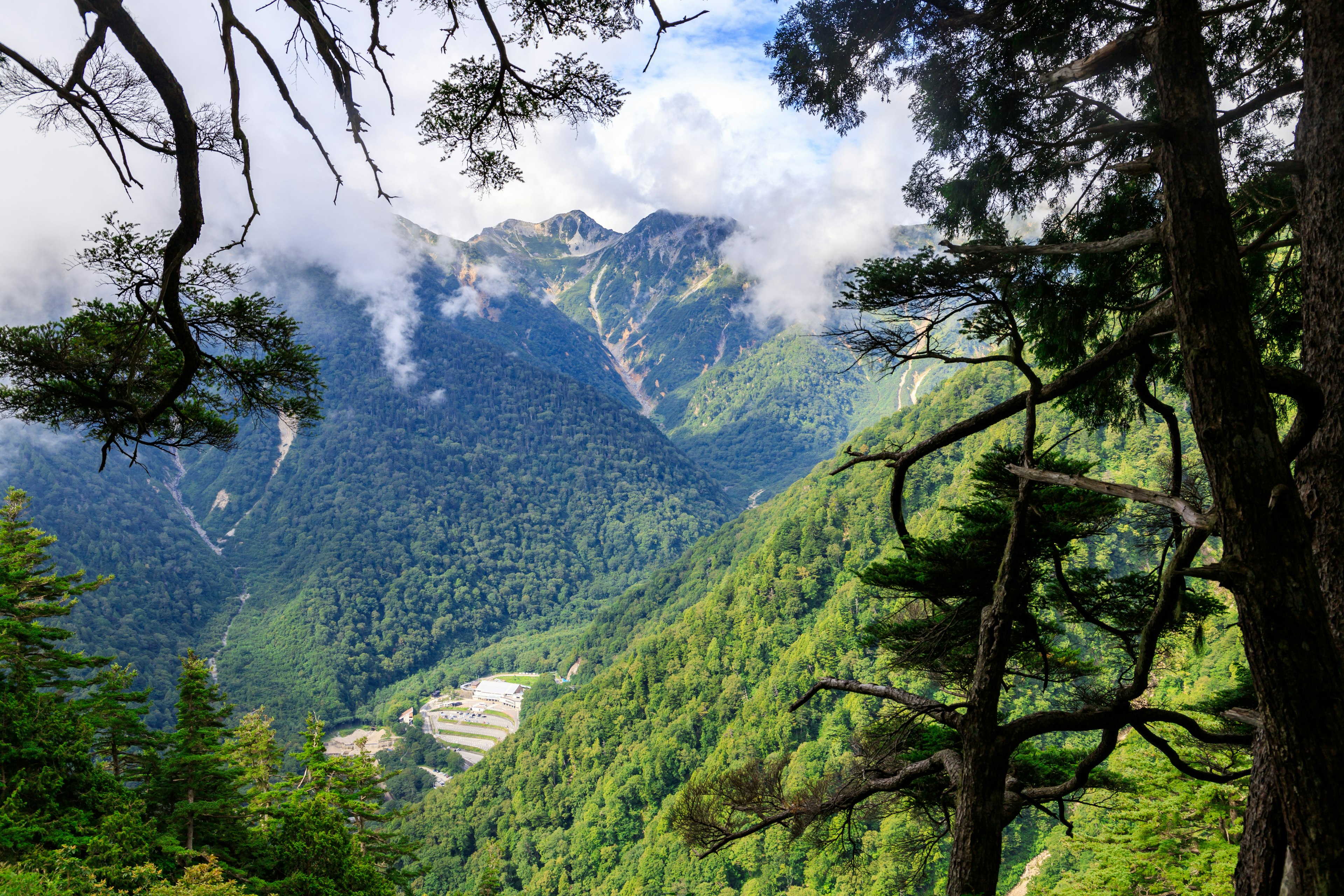 Valle verdeggiante circondata da montagne e nuvole