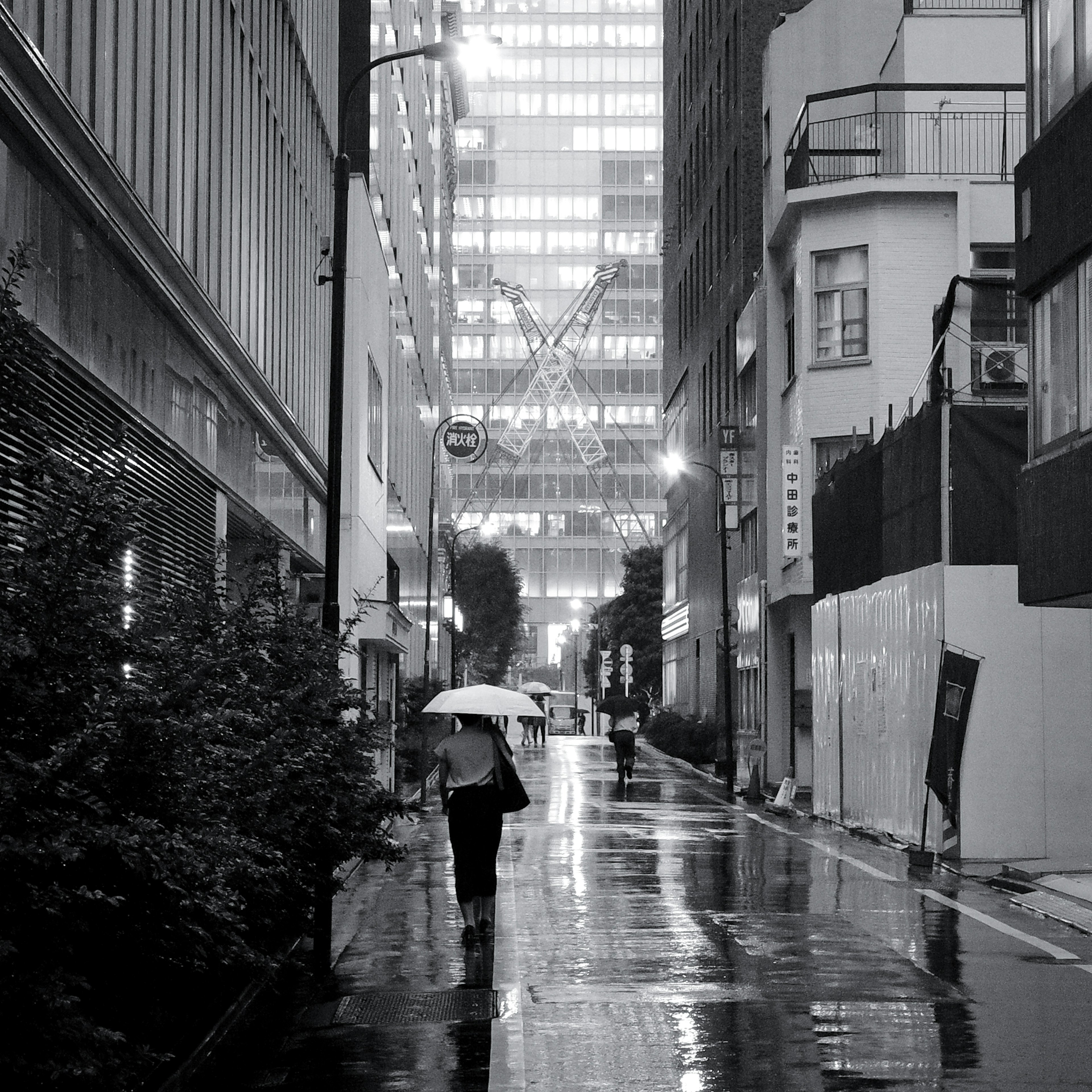 Une personne marchant avec un parapluie dans un paysage urbain monochrome sous la pluie