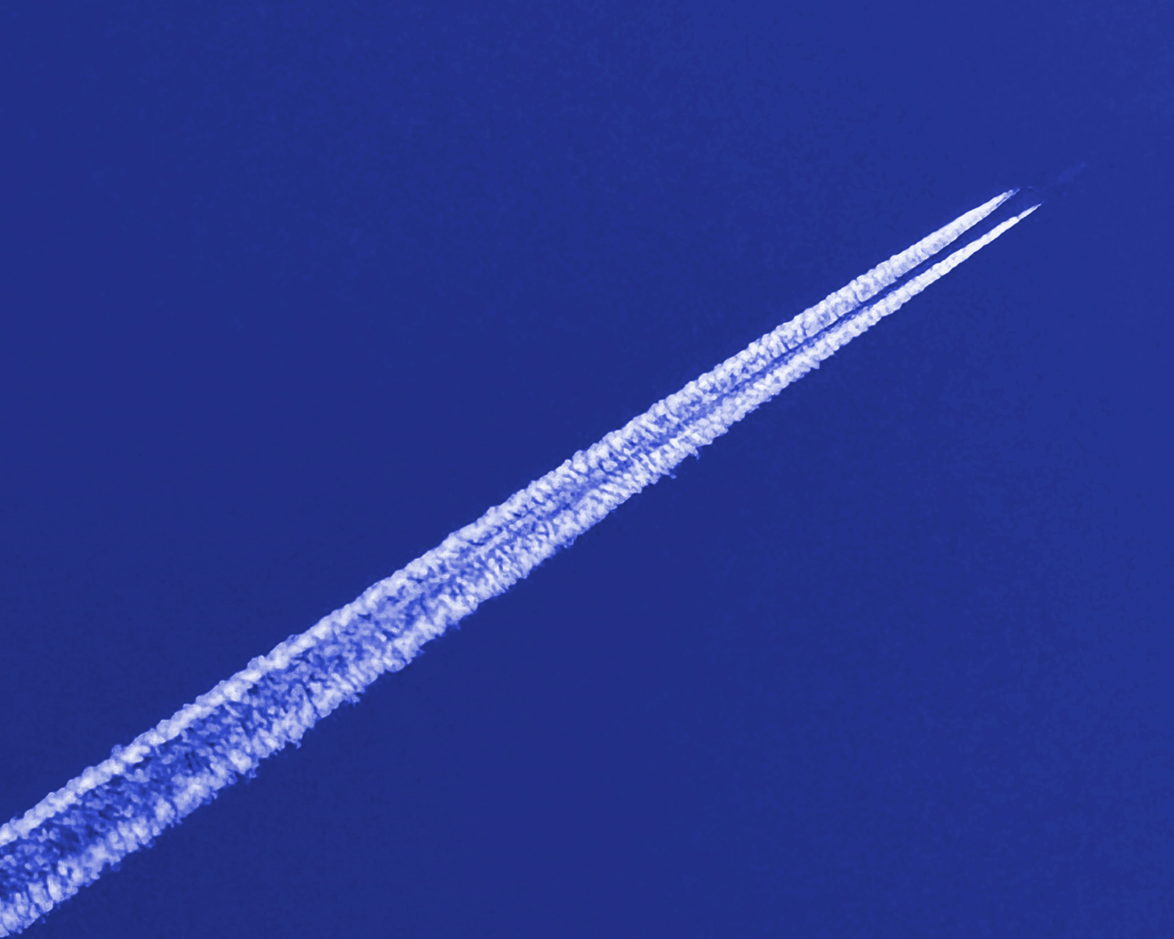 White contrails streaking across a deep blue sky