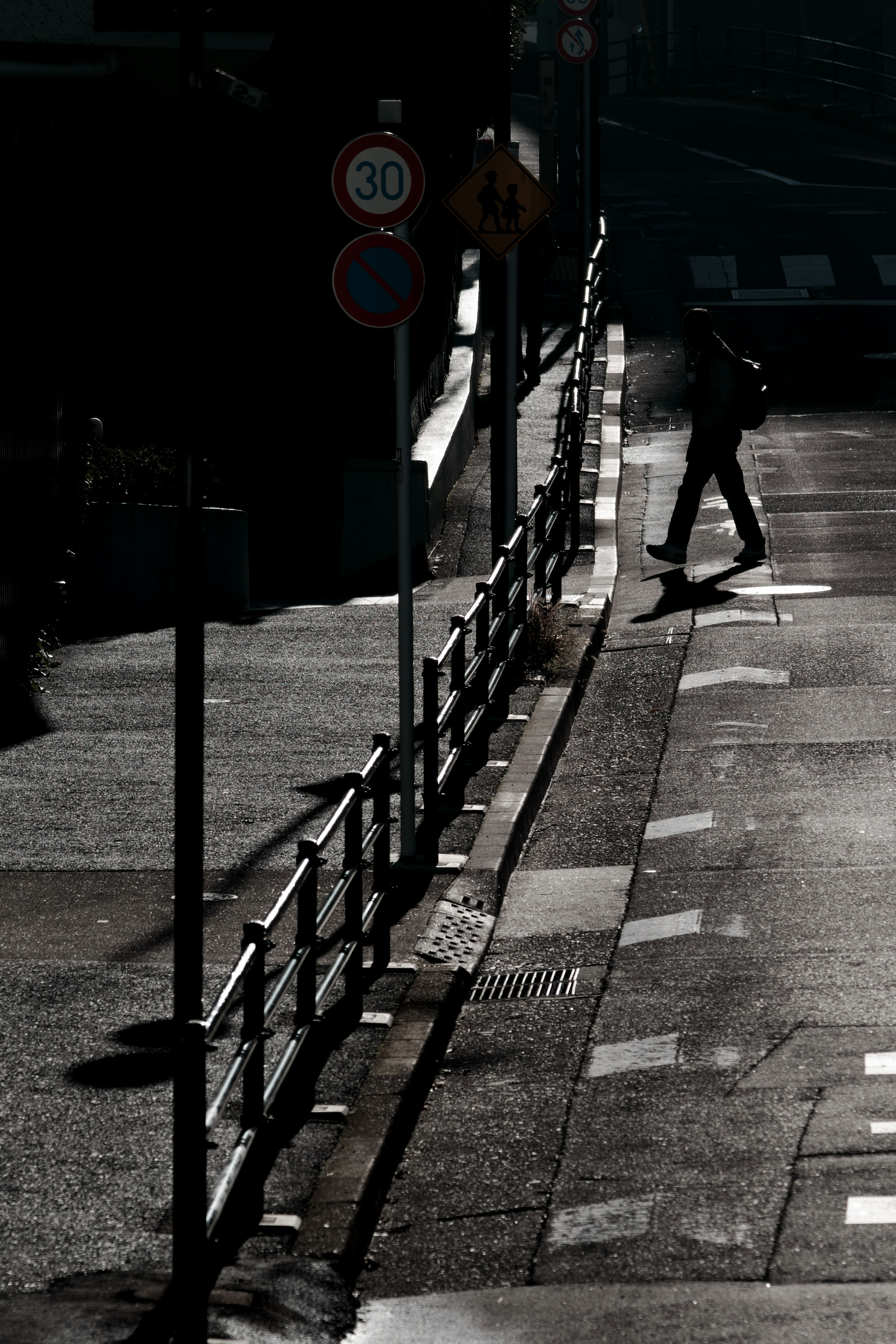 Eine Person geht auf einer dunklen Straße mit Schatten und Verkehrszeichen