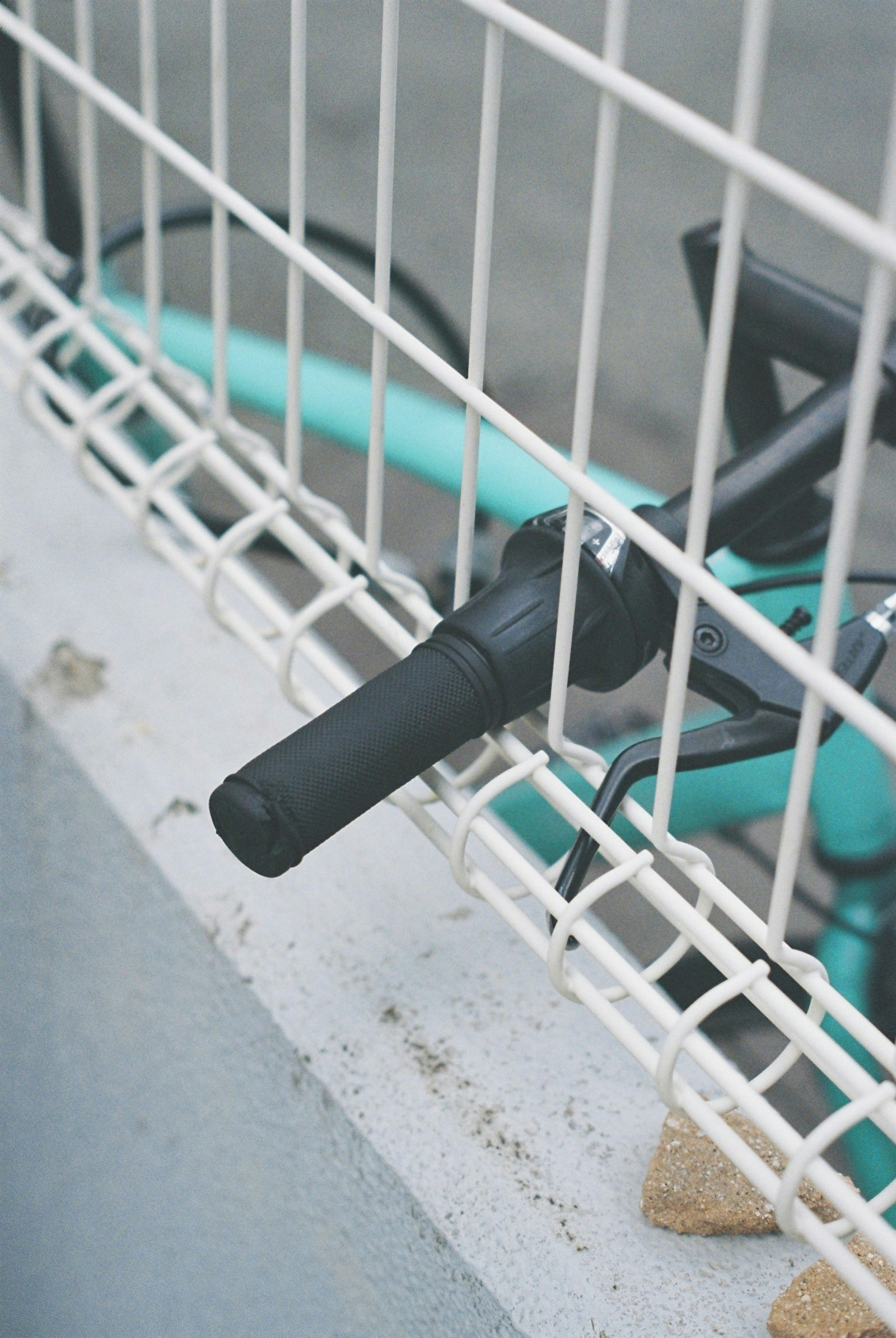 A bike lock attached to a white fence with a turquoise background