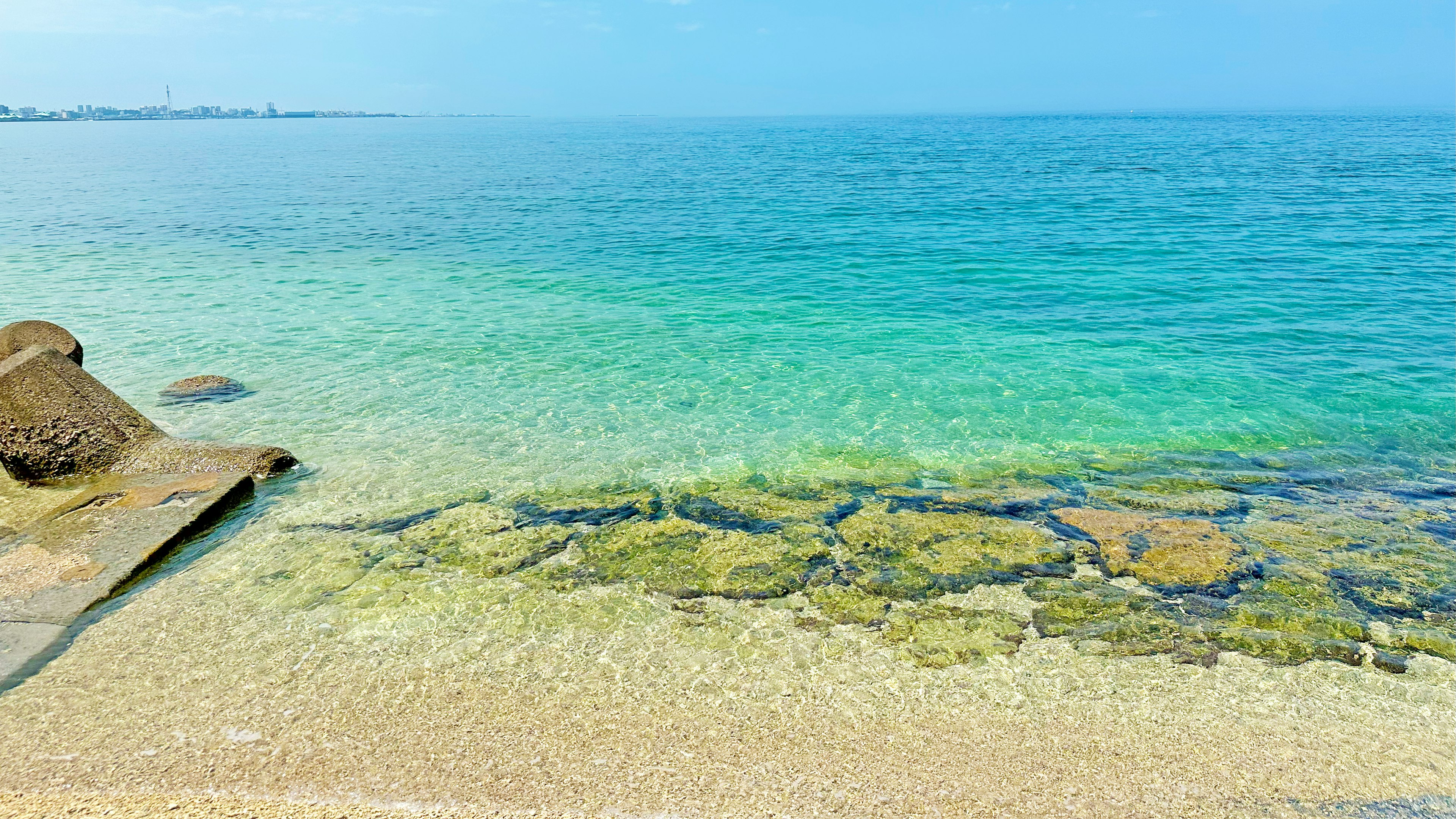 ทิวทัศน์ที่สวยงามของทะเลสีน้ำเงินและน้ำตื้น พร้อมหินและชายหาดทราย