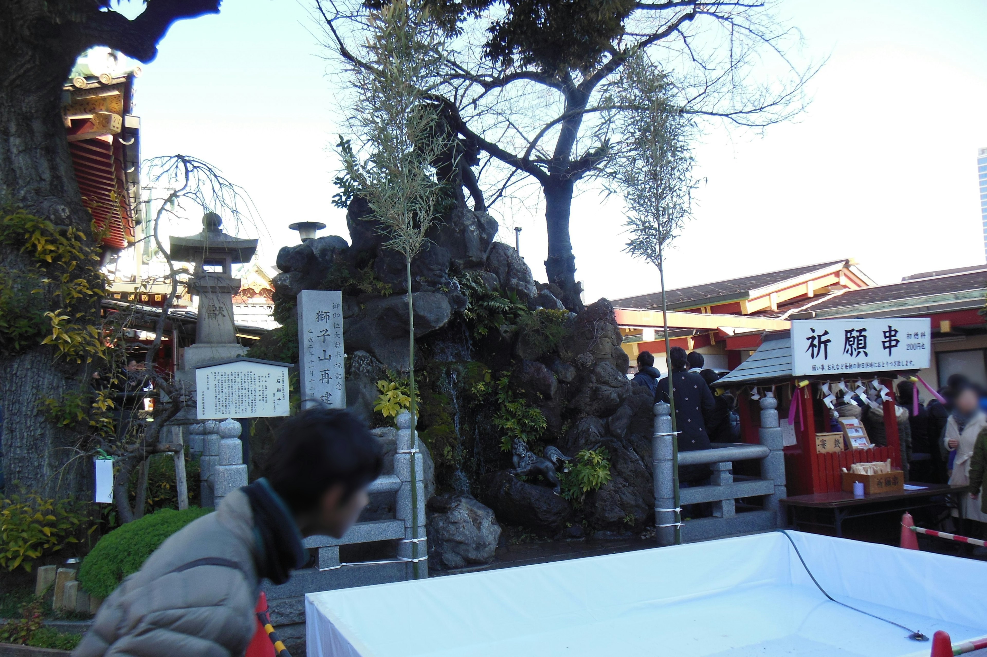 神社の境内にある大きな岩と木々の風景多くの人々が行き交う様子