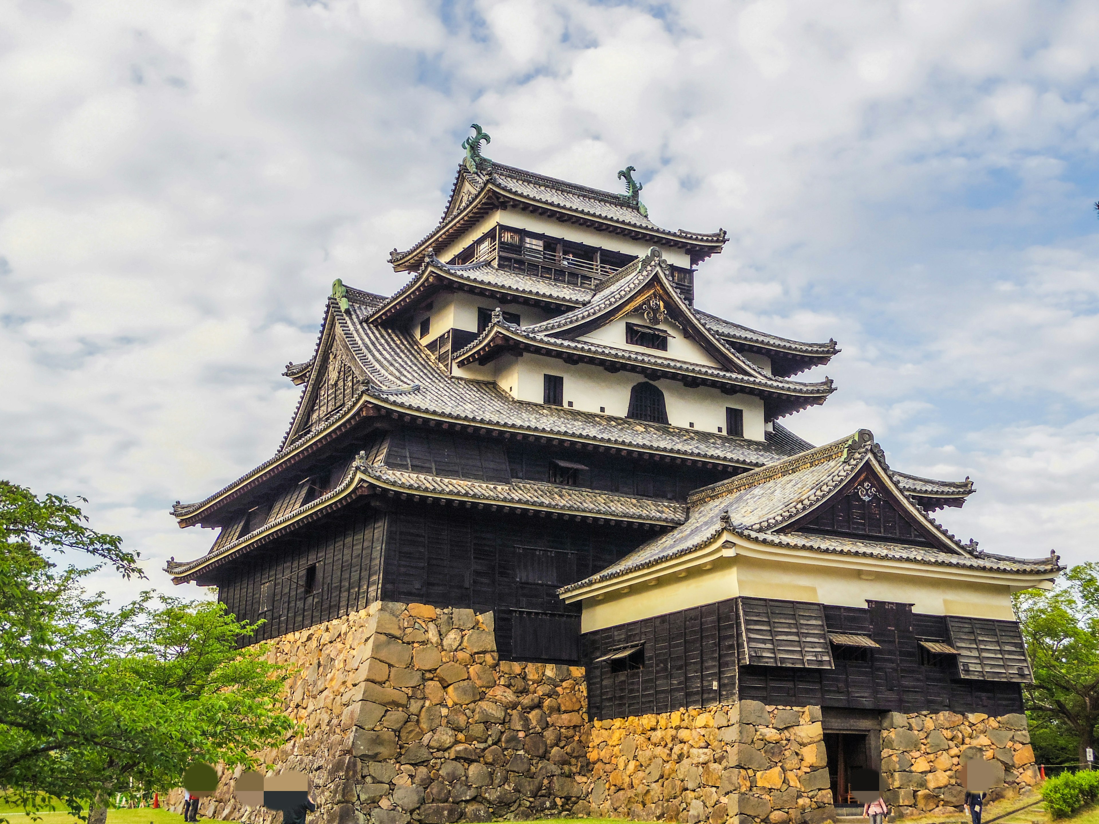 Kastil Jepang tradisional dengan dinding batu hitam dan atap yang dihias