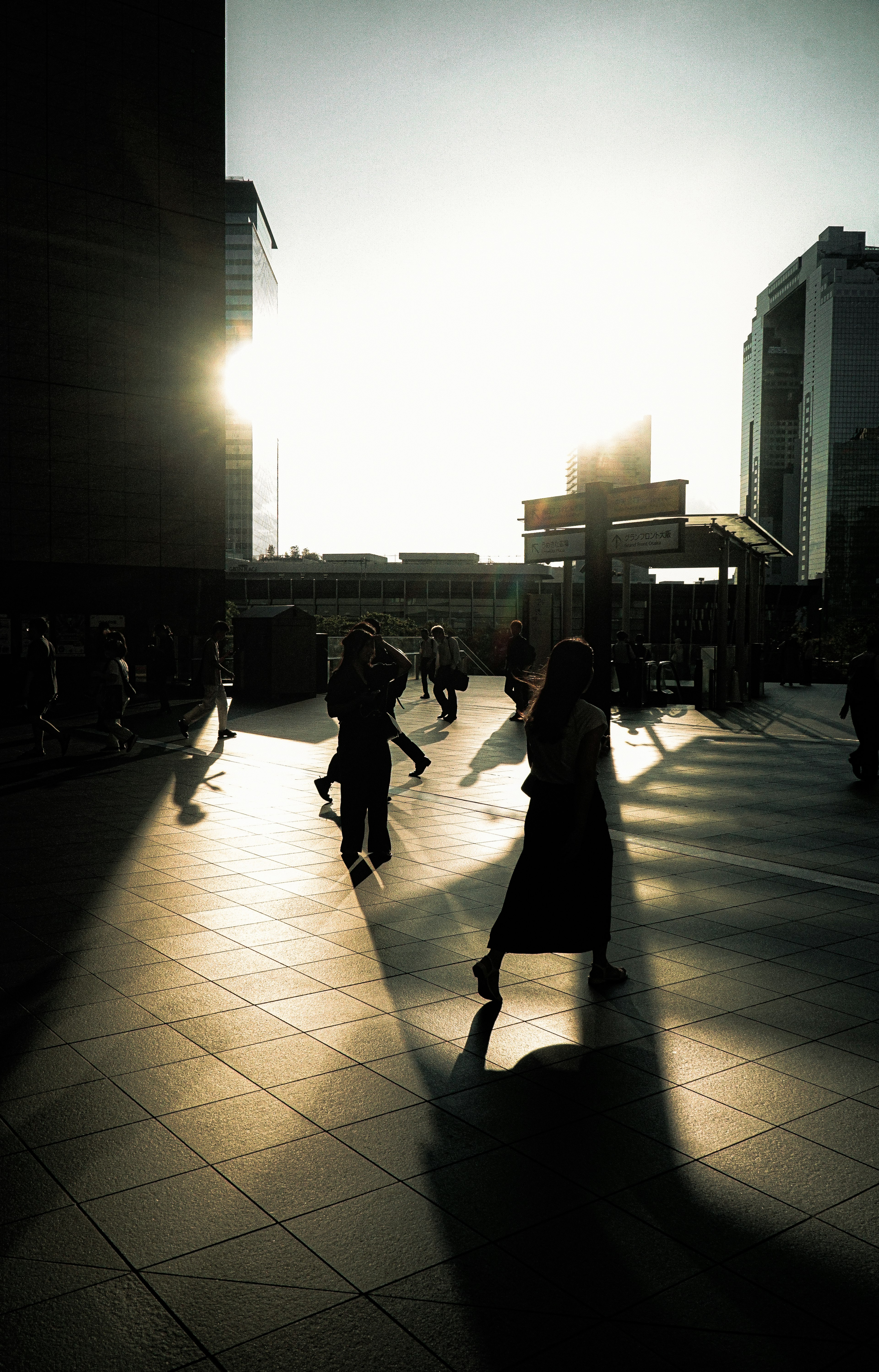 Silhouetten von Menschen, die in der Stadt gegen den Sonnenuntergang gehen