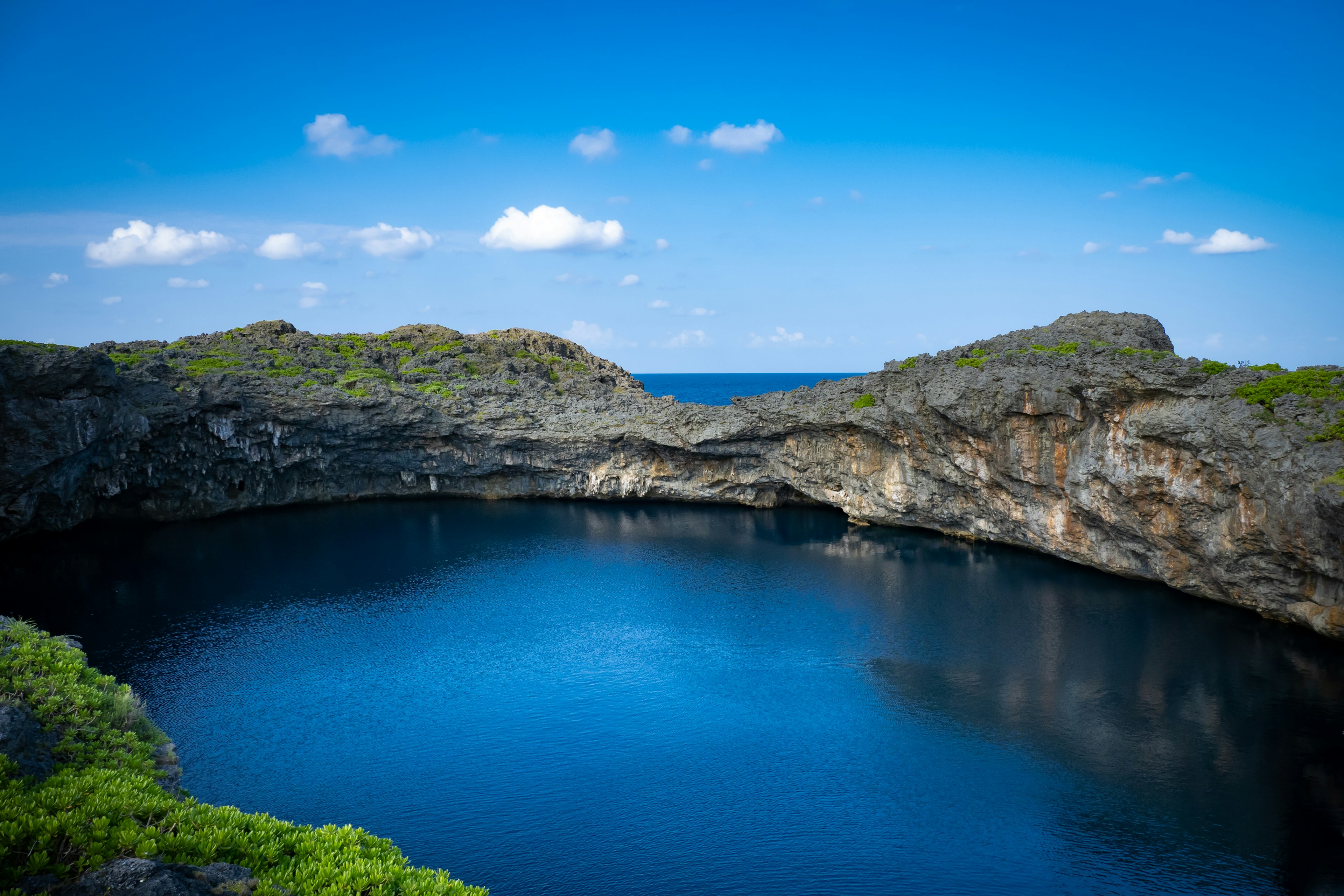 Estanque natural rodeado de rocas y mar azul