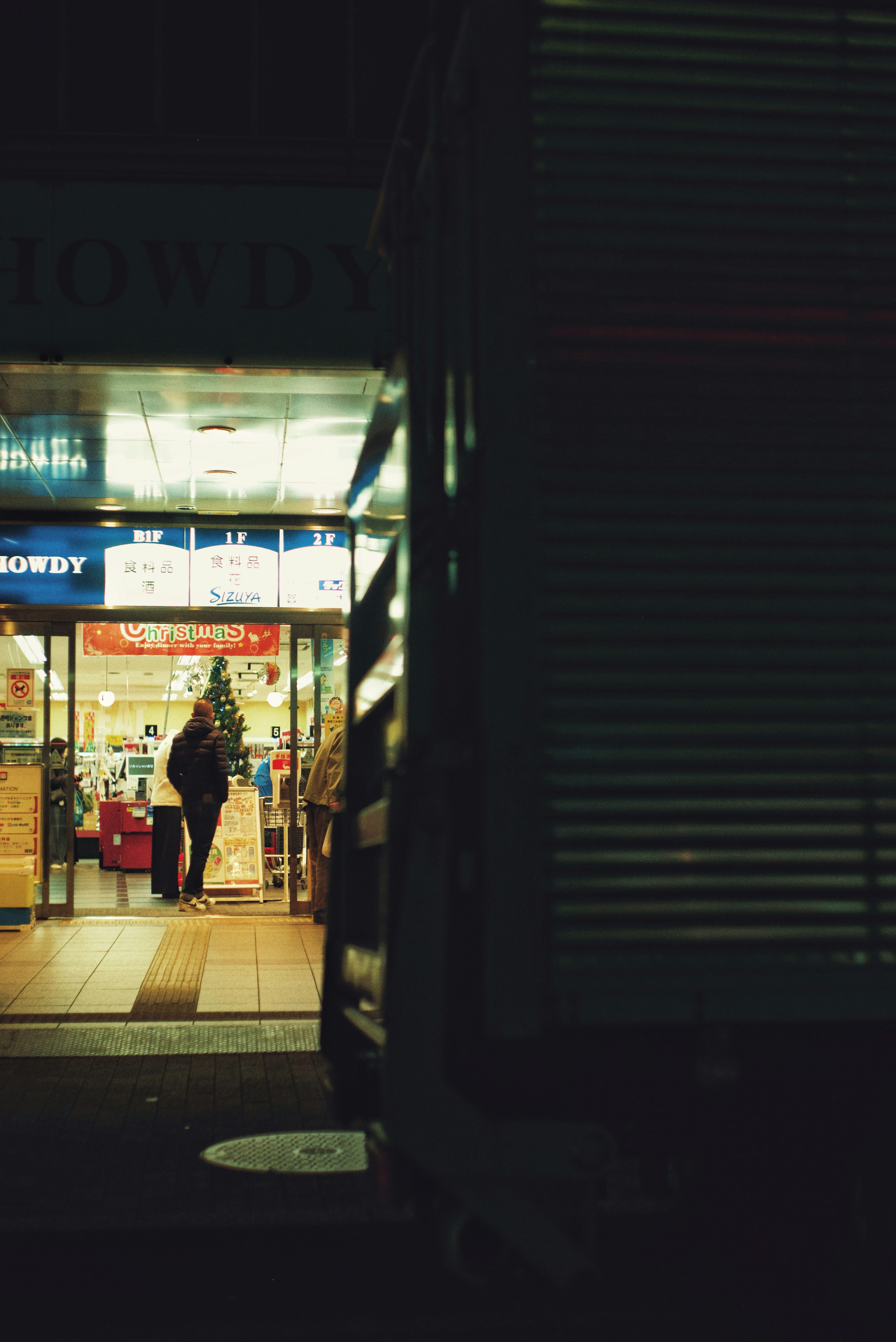 Una persona de pie frente a la entrada de una tienda iluminada por la noche