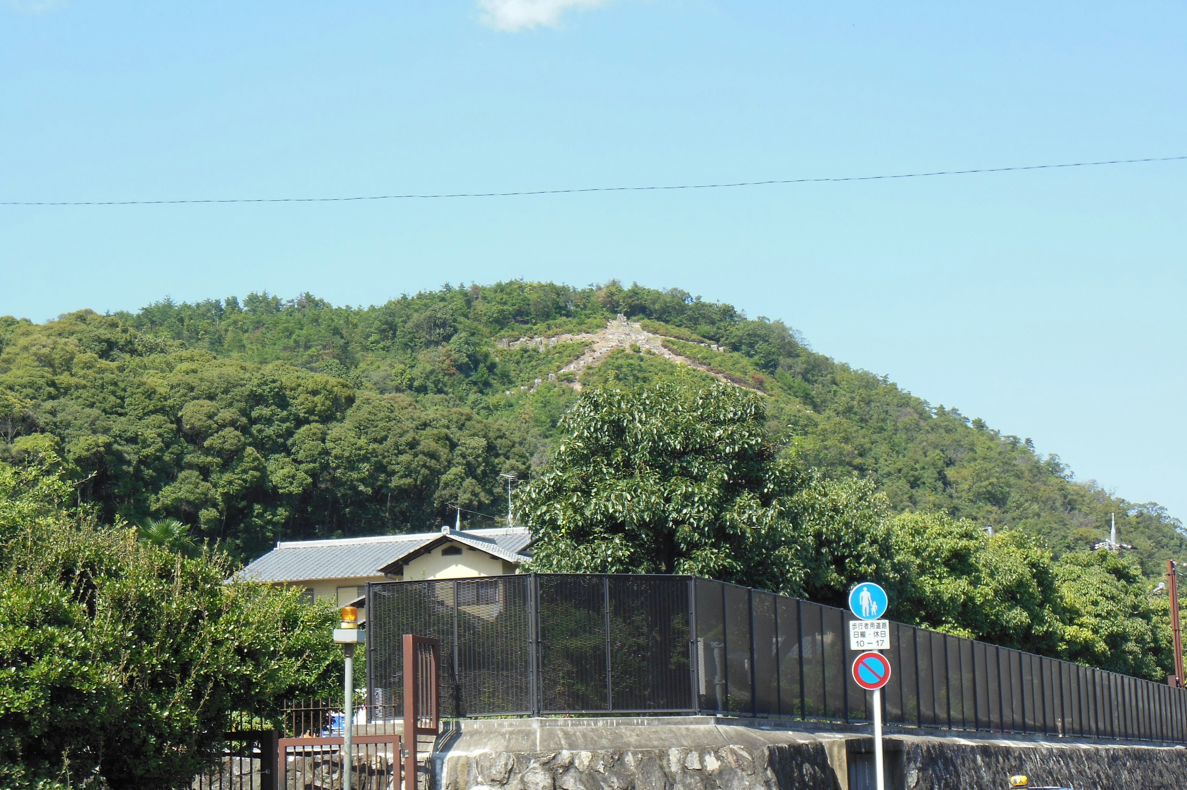 Vue panoramique d'une colline verdoyante avec des panneaux de signalisation au premier plan