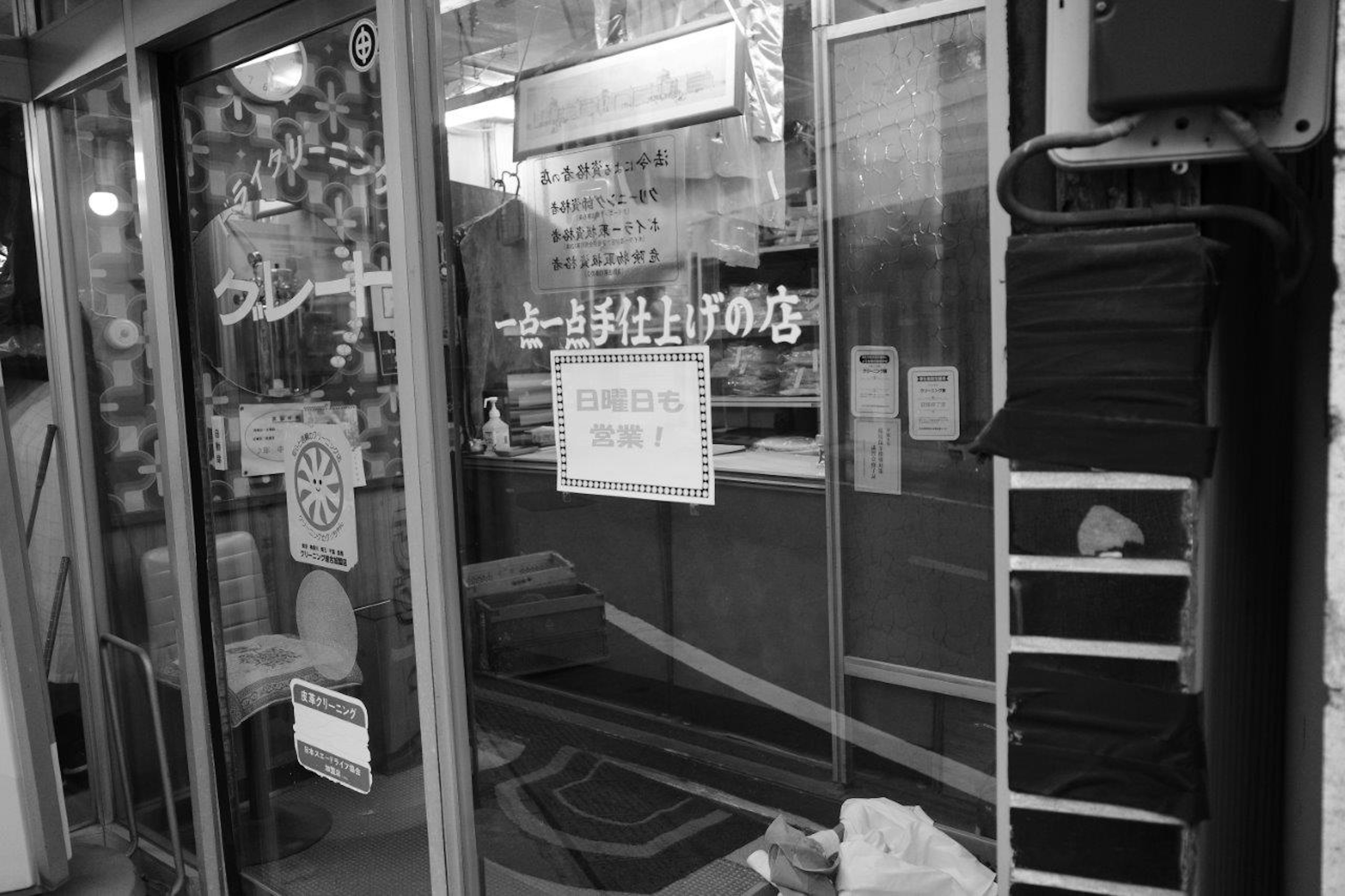 Entrance of a shop with various posters and signs in black and white